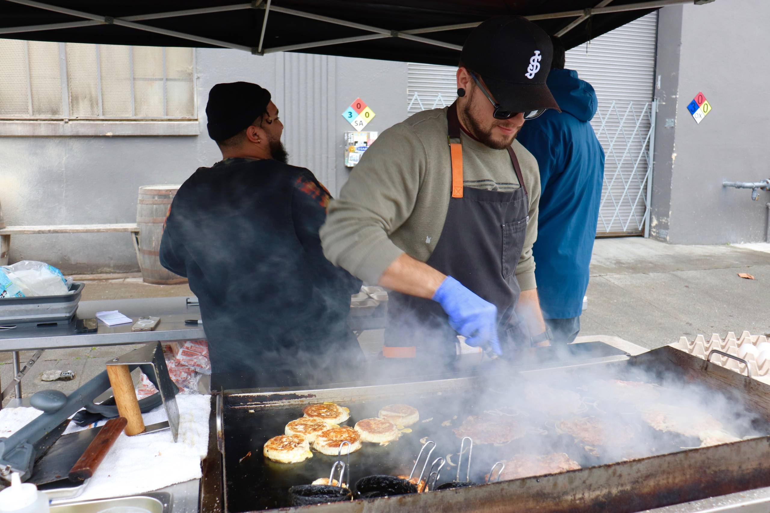 three food workers prepare food and man an outdoor pop-up business in West Oakland