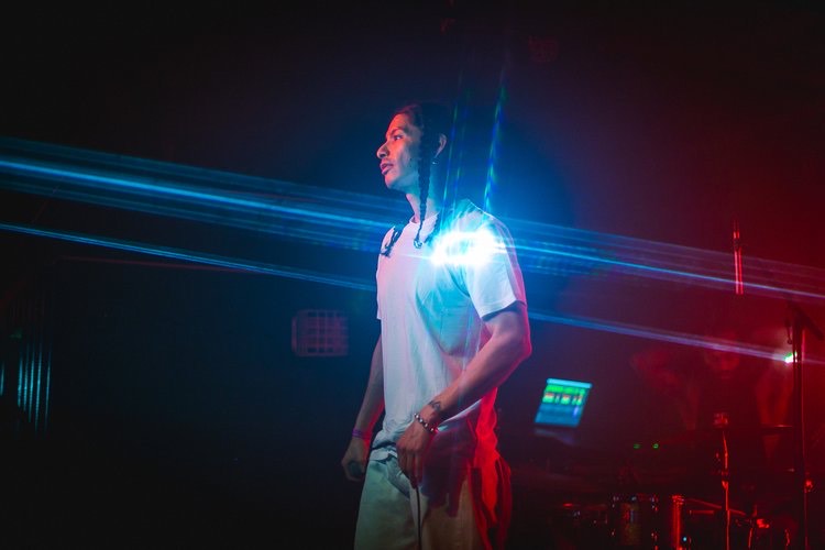 a Peruvian rapper is on a darkly lit stage during a music performance