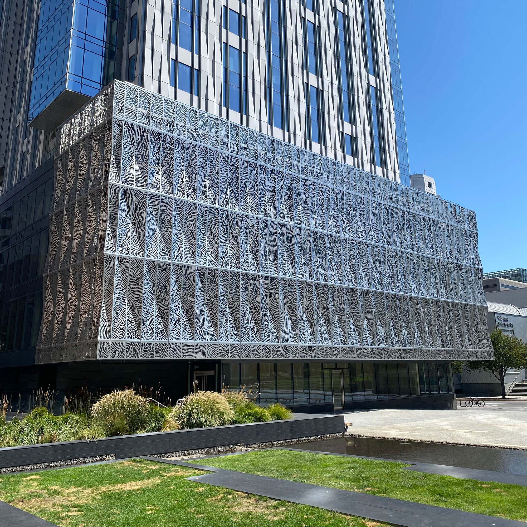 Decorative metal facade at base of taller tower fronting plaza
