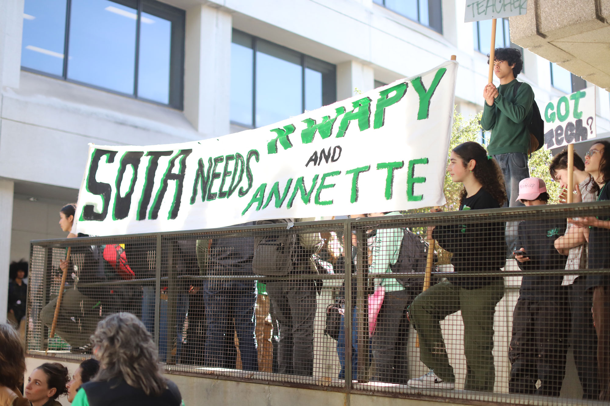 Young people hold a large painted banner reading "SOTA needs Kwapy and Annette"