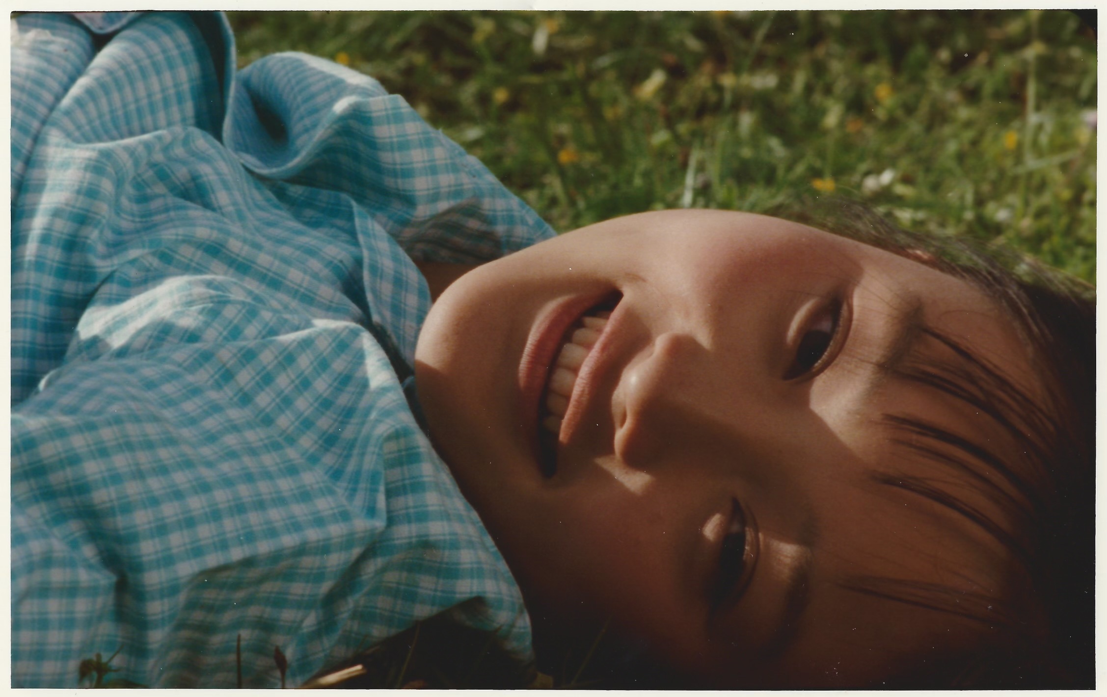Young person smiles while laying on grass
