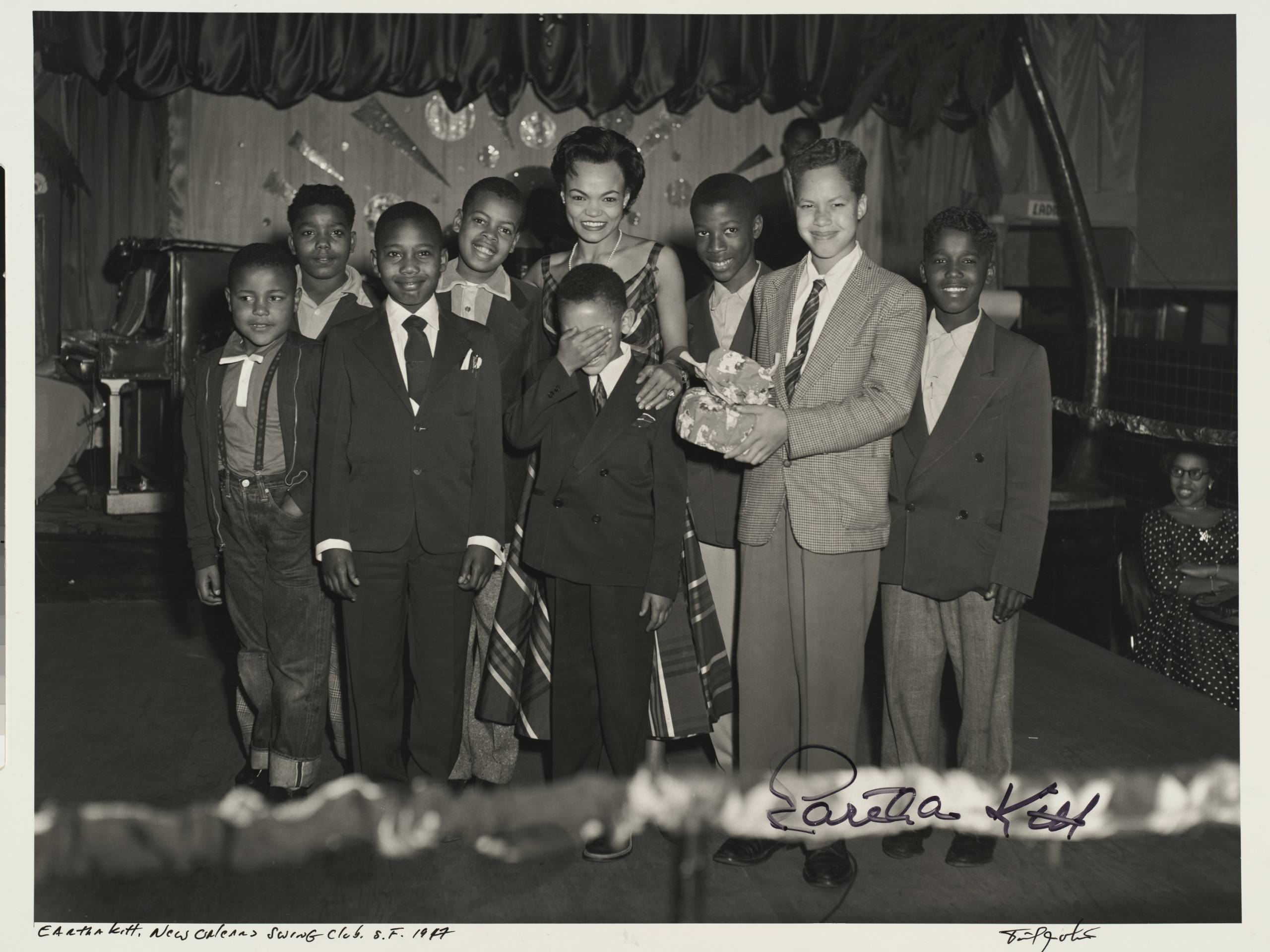 Signed black-and-white photograph of woman posing with children on a stage