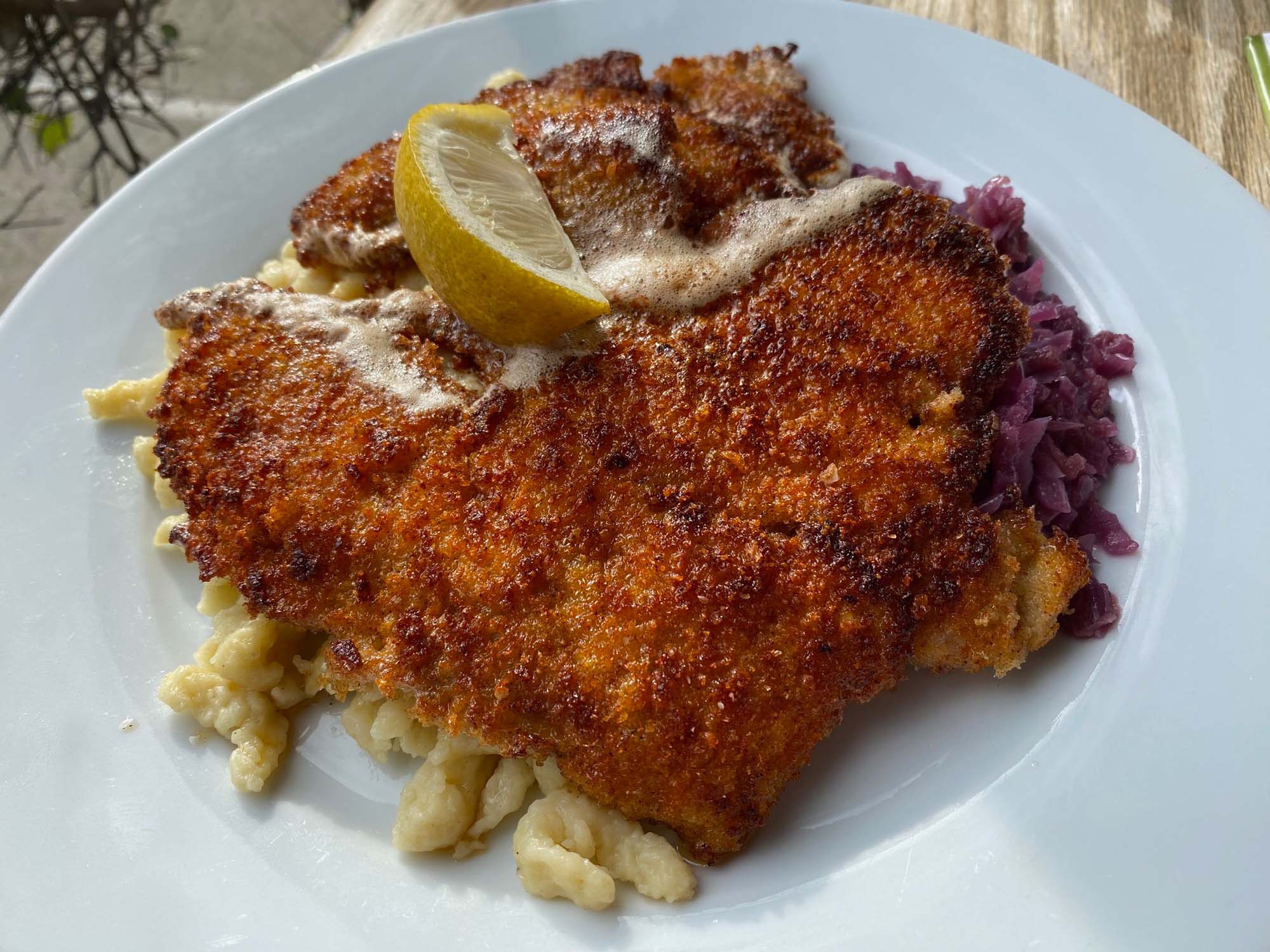 Pork schnitzel over a bed of spätzle, topped with a lemon wedge.