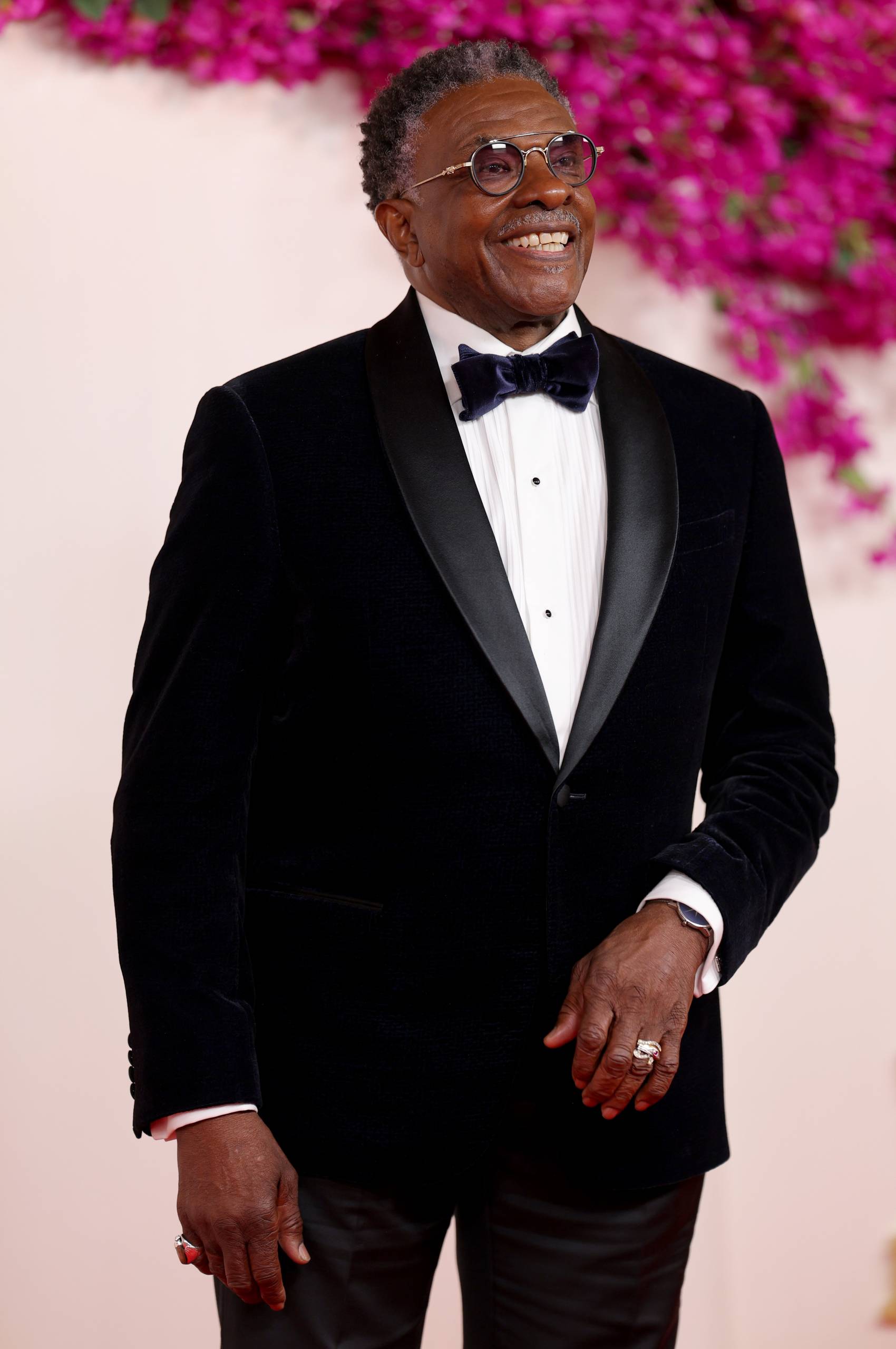 A Black man in a tuxedo smiles warmly.