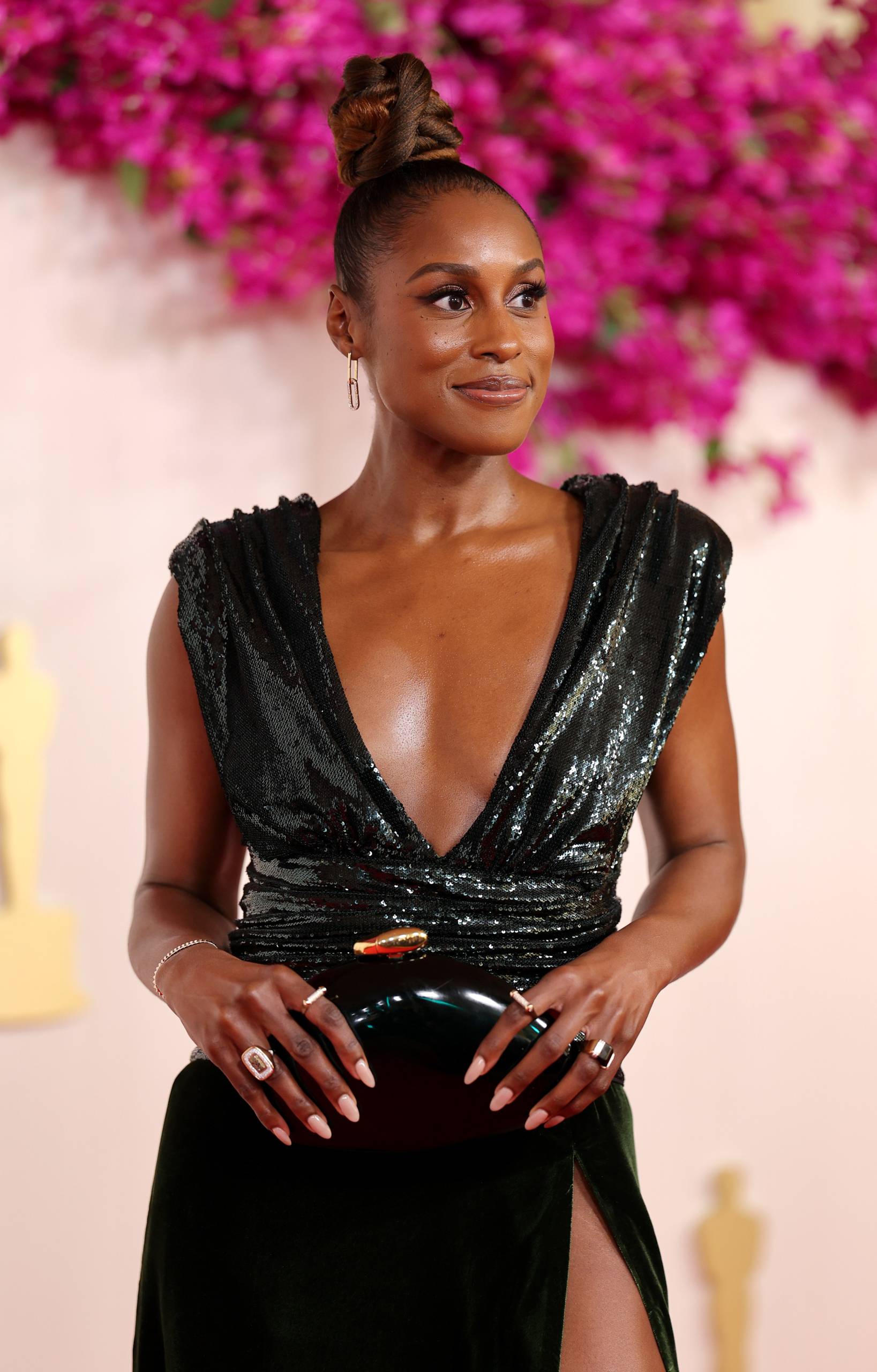 A Black woman wears a plunging black sequined gown. 
