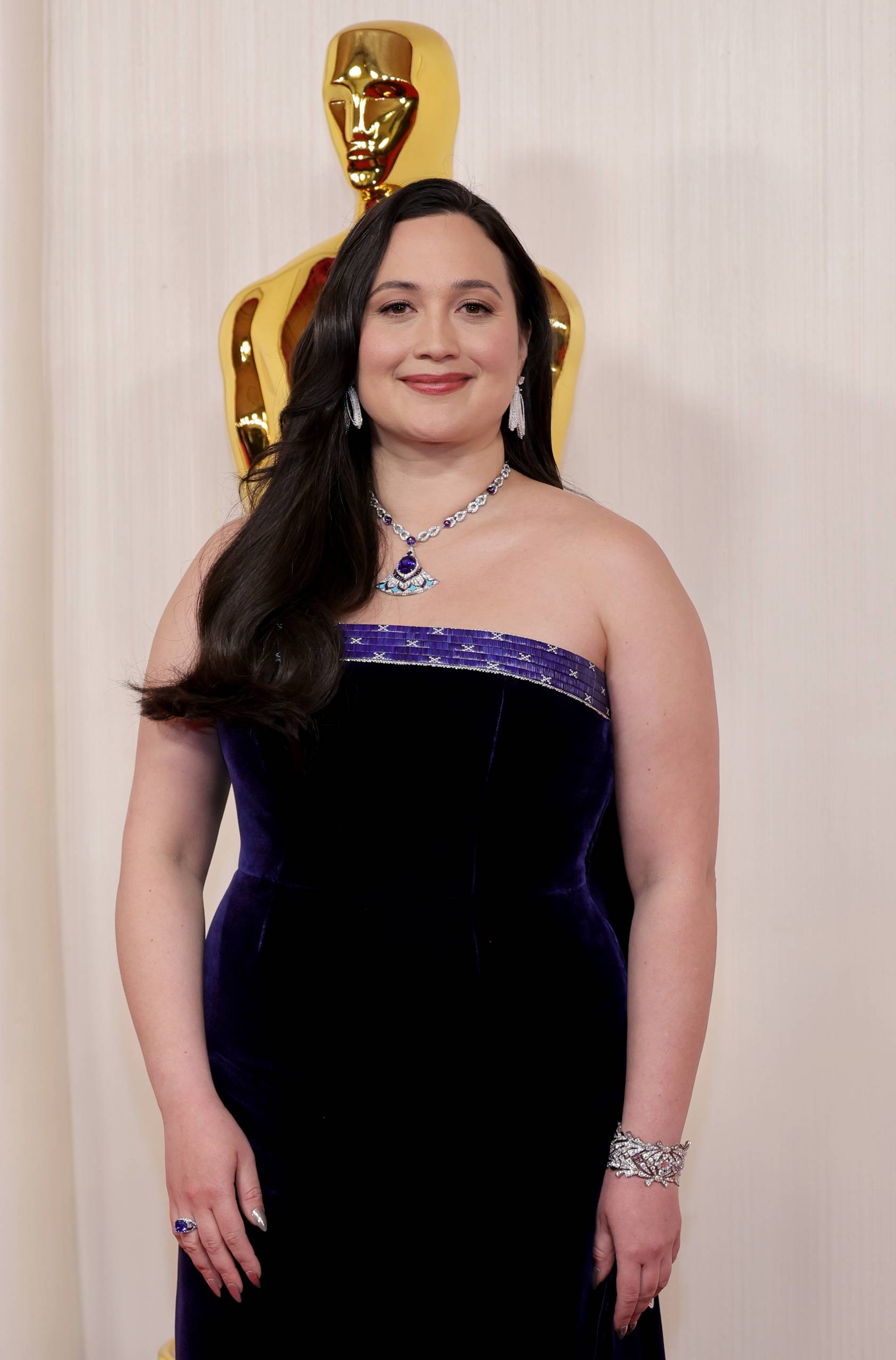 An Indigenous woman wears a strapless purple gown and jewels.