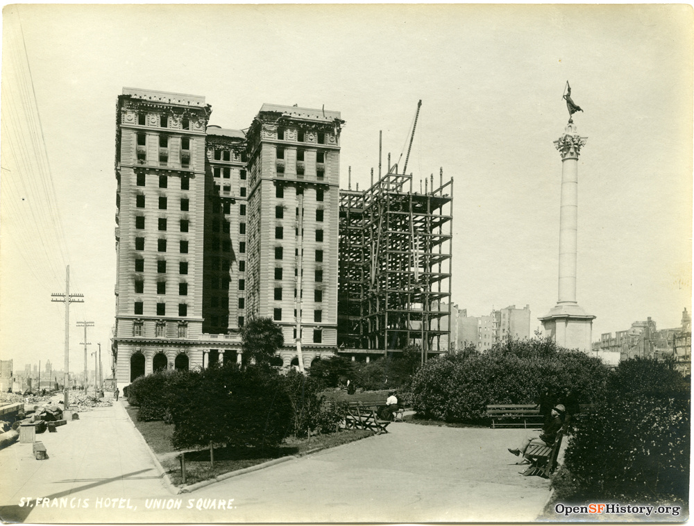 A sepia-toned photograph of a tall, burned out building with two towers intact and a third under construction.