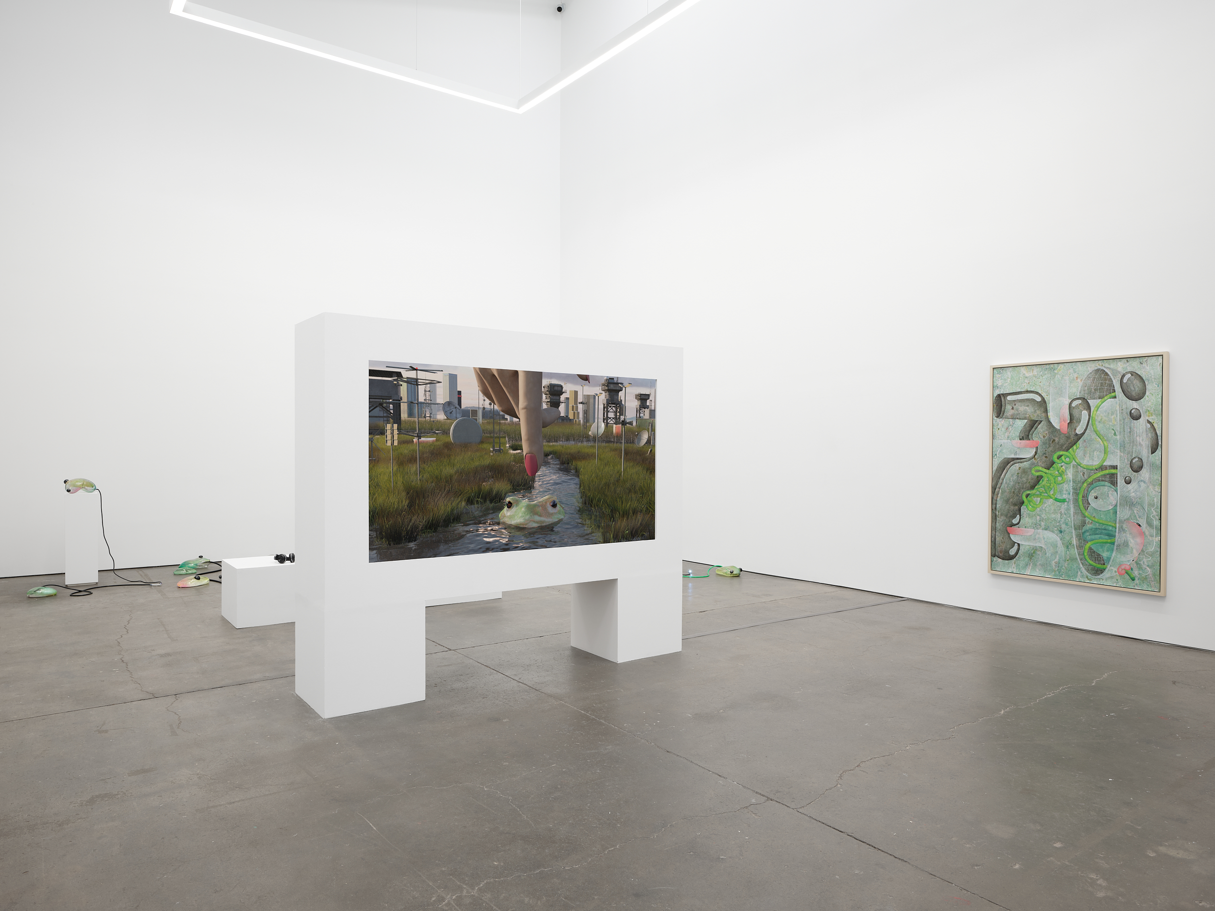 White gallery with large painting, sculptures in back and freestanding wall with embedded video screen