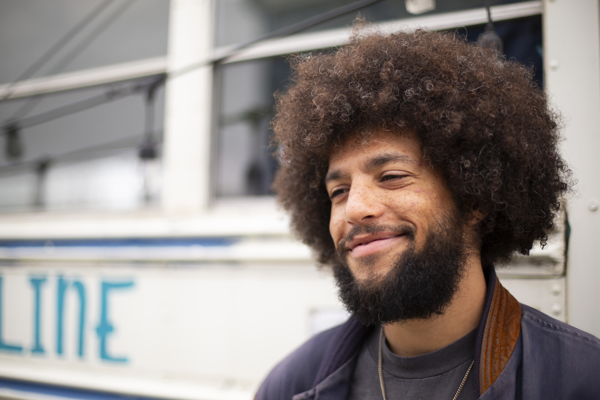 A young rapper and producer poses in front of an old school bus.