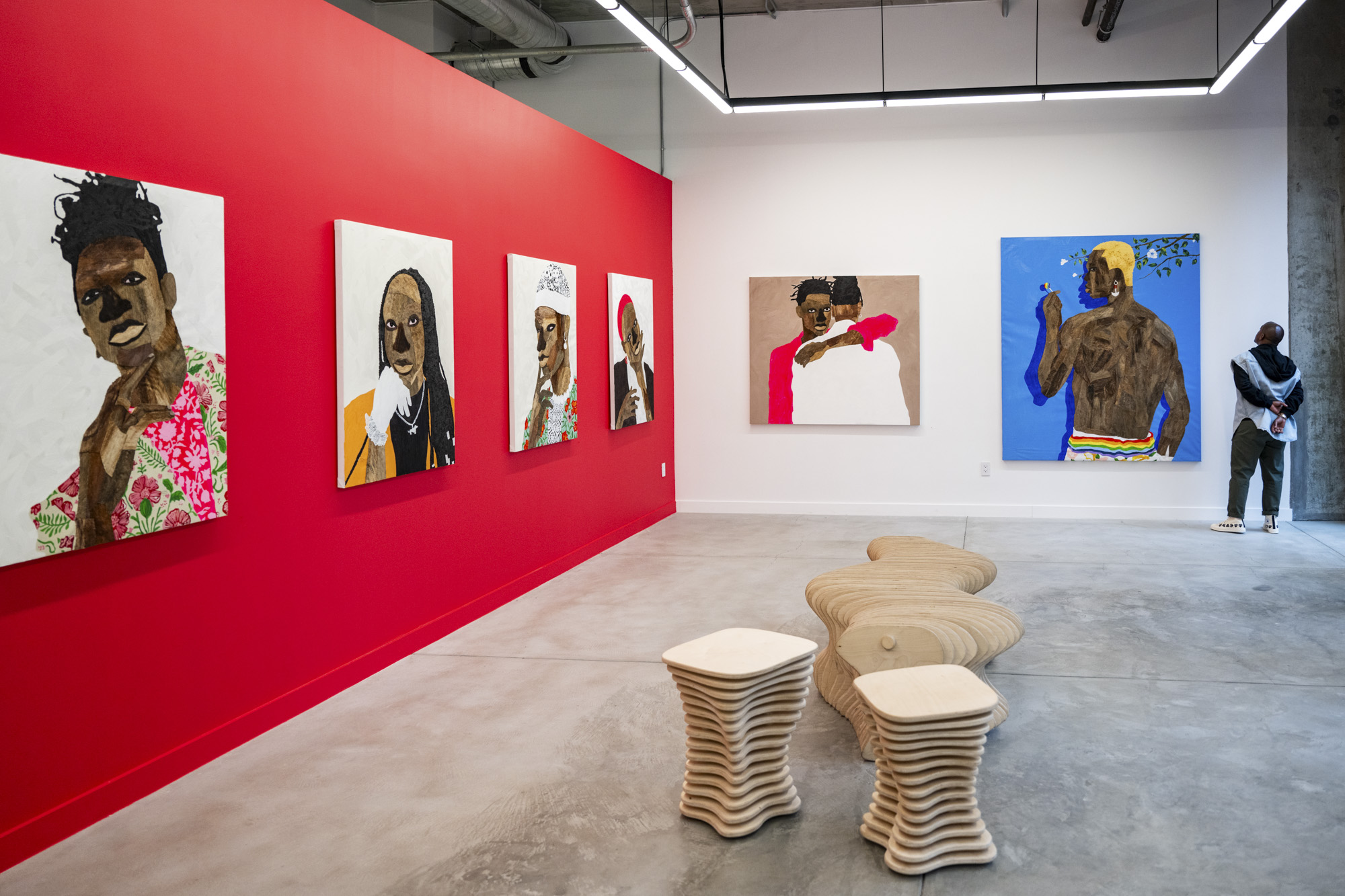 Small figure looks at large-scale portrait paintings in gallery space
