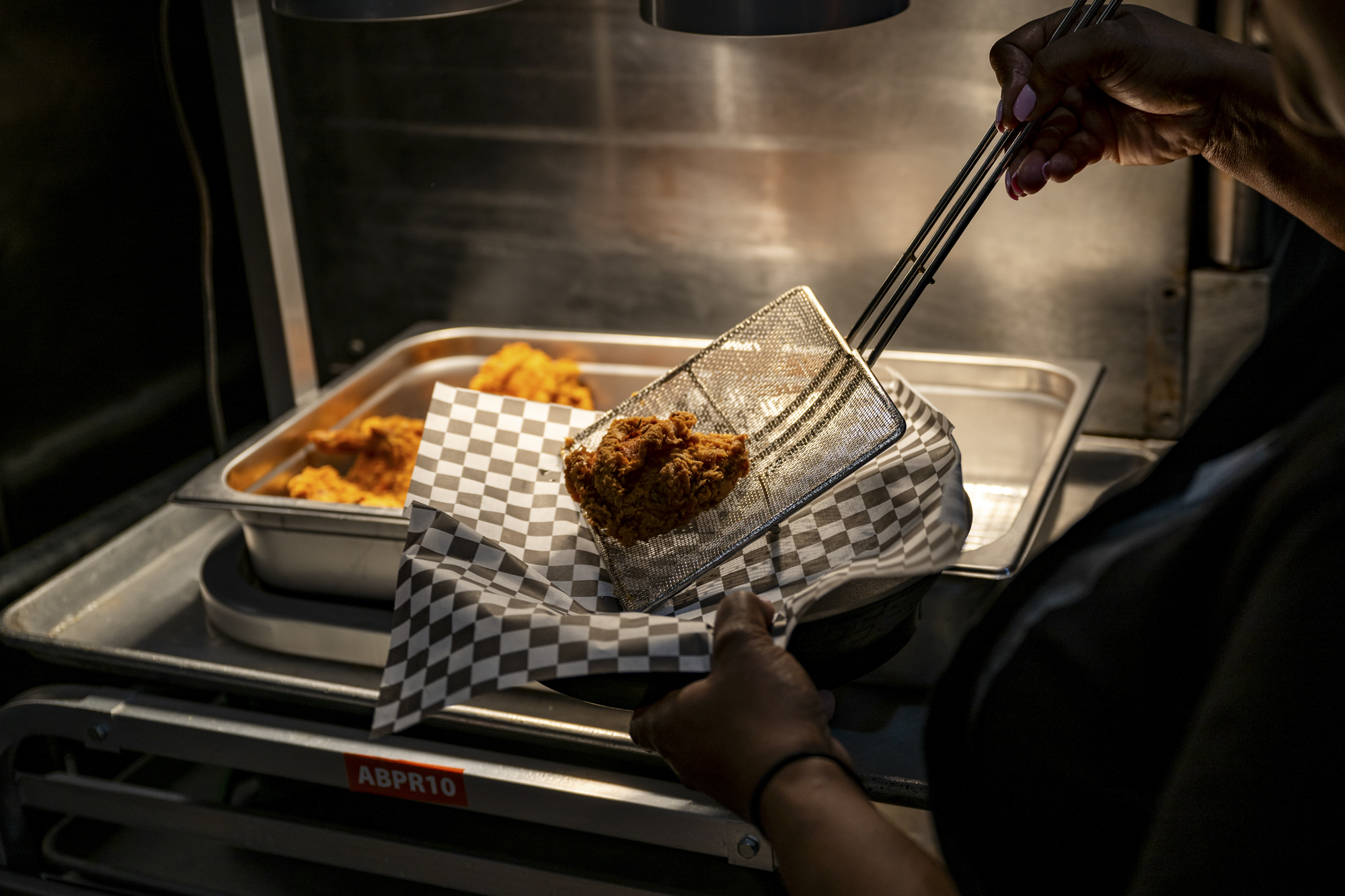A fresh batch of fried chicken is pulled out of the deep fryer.