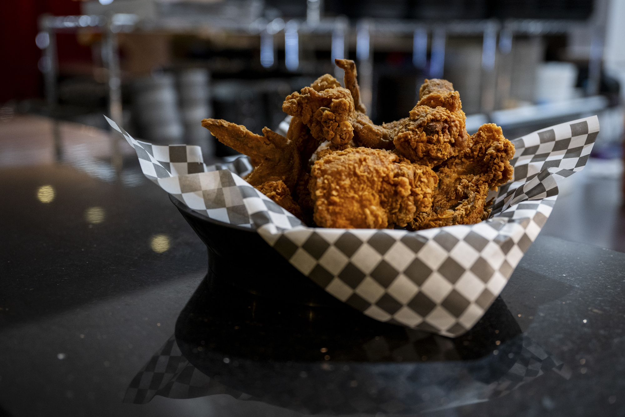 A paper-lined basket of fried chicken on a countertop.