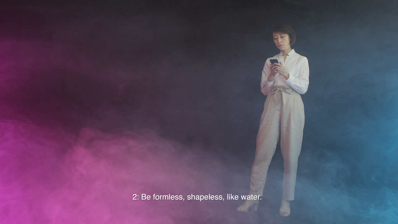 Person stands looking at phone, text below reads "2: Be formless, shapeless, like water."