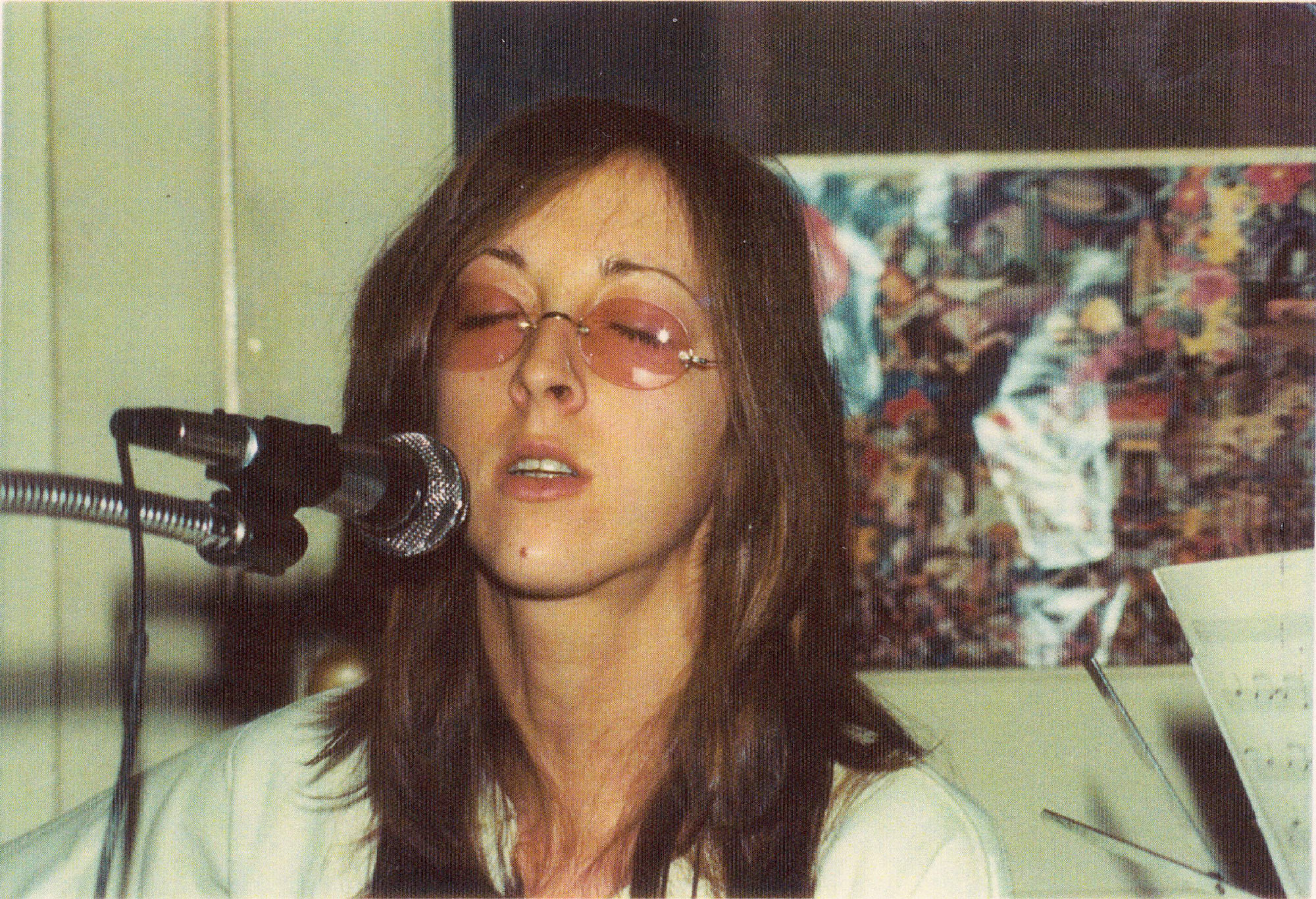 Person with eyes closed singing into mic with rose-colored glasses