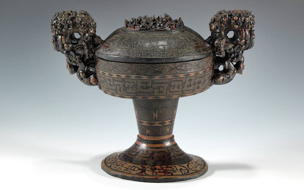 Lidded ancient Chinese food vessel with ornately carved handles.