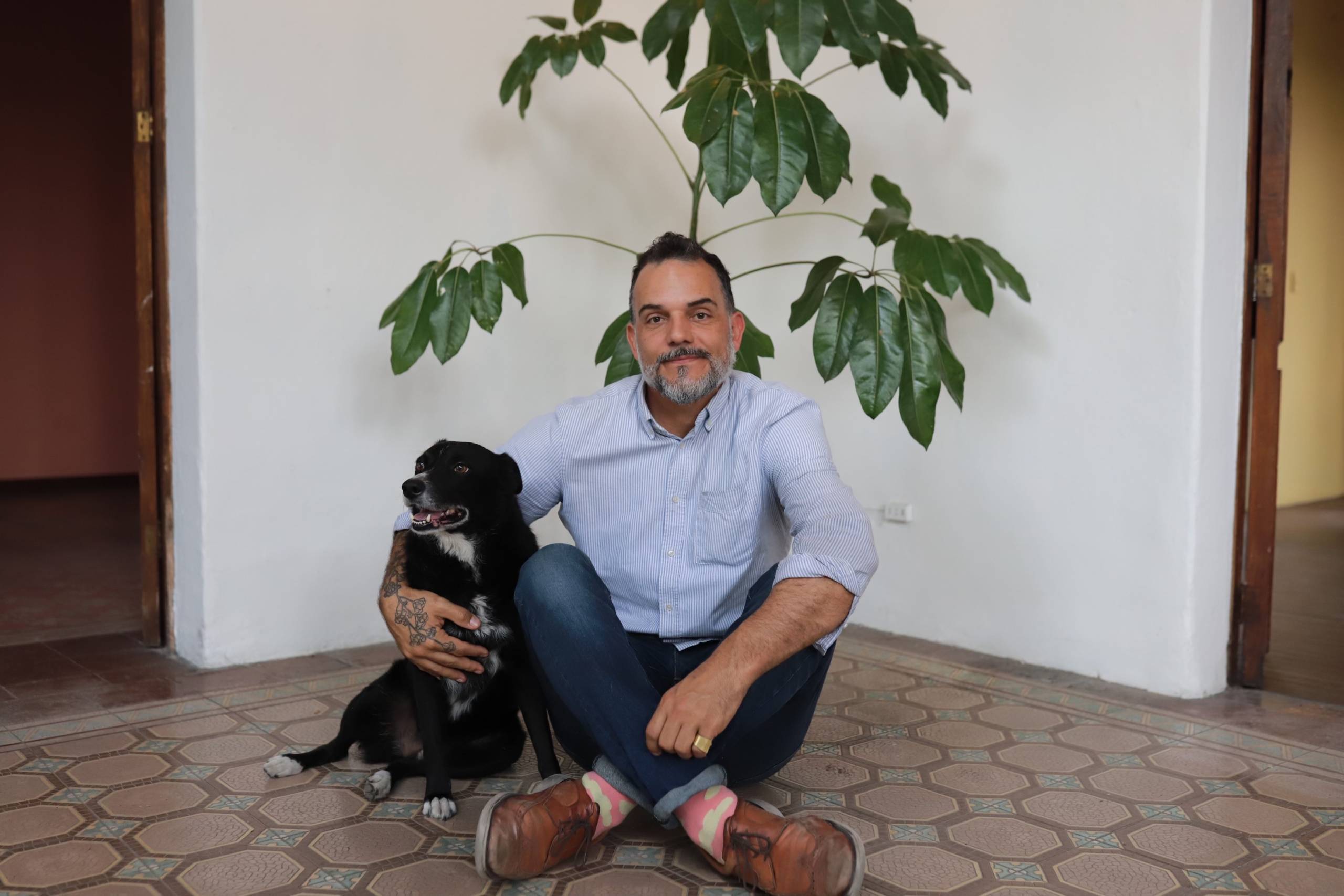 a man and his dog sit in front of a plant at his home in southern Mexico