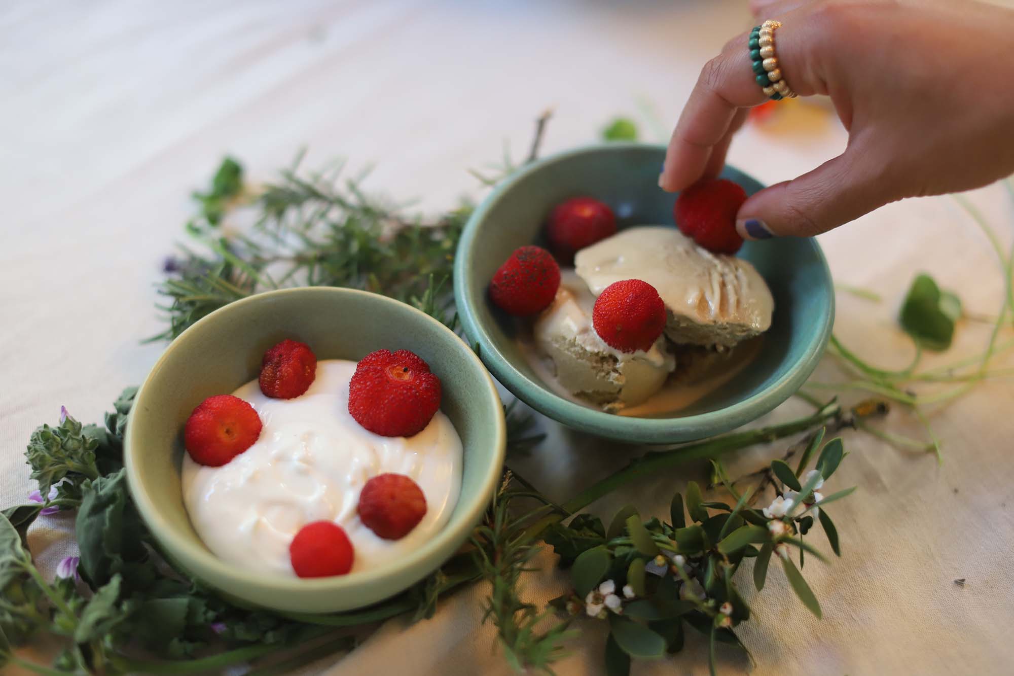 Red berries arranged on top of bowls of whipped cream and ice cream.