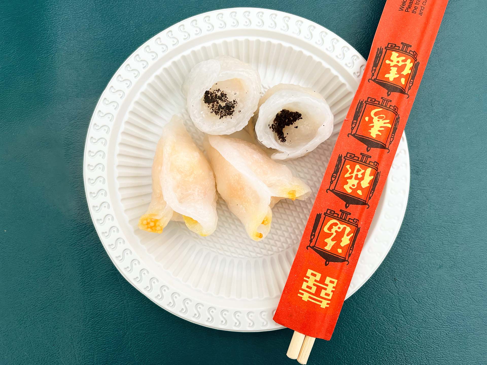 Two varieties of dim sum on a paper plate. One of them is topped with black truffle shavings.