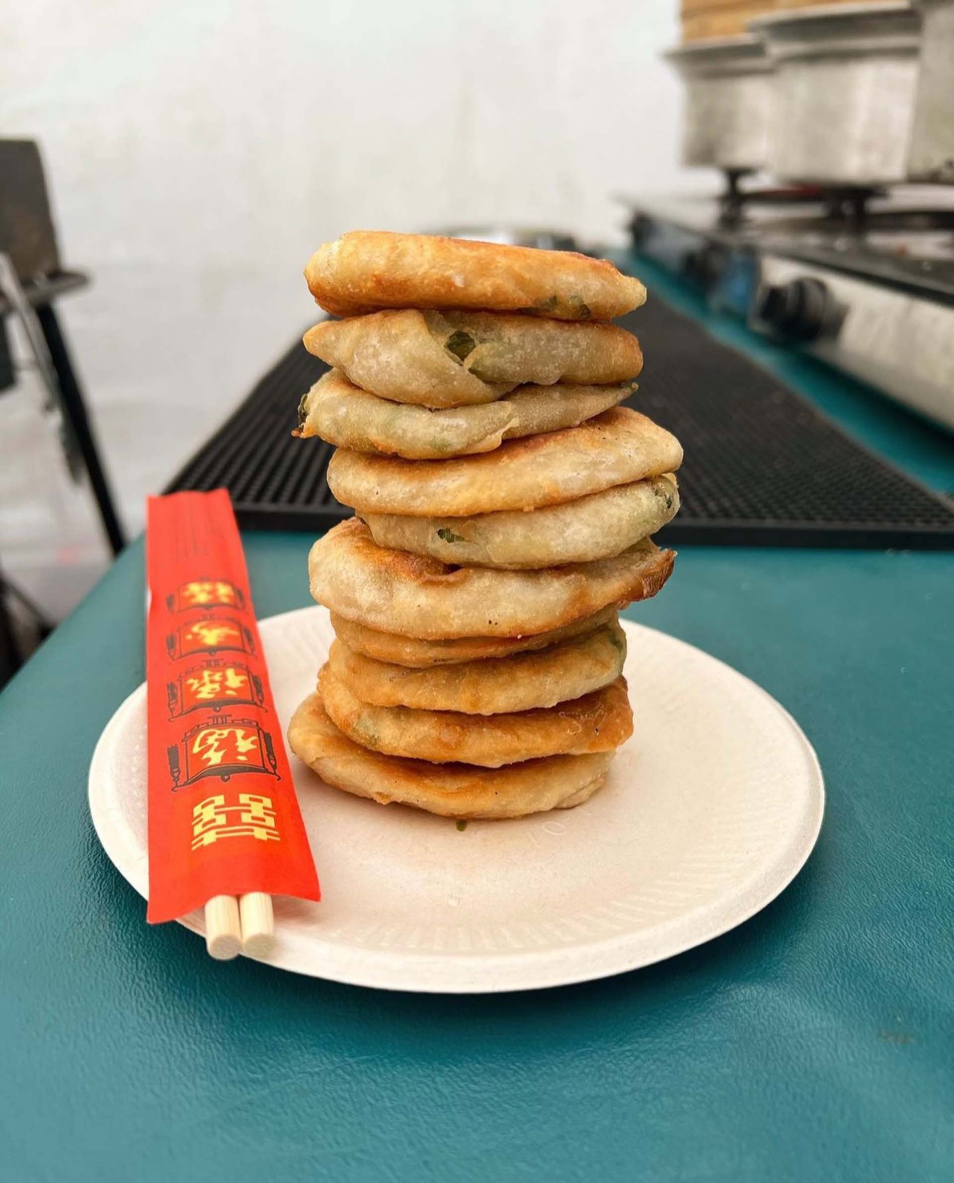 A stack of scallion pancakes on a white plate.