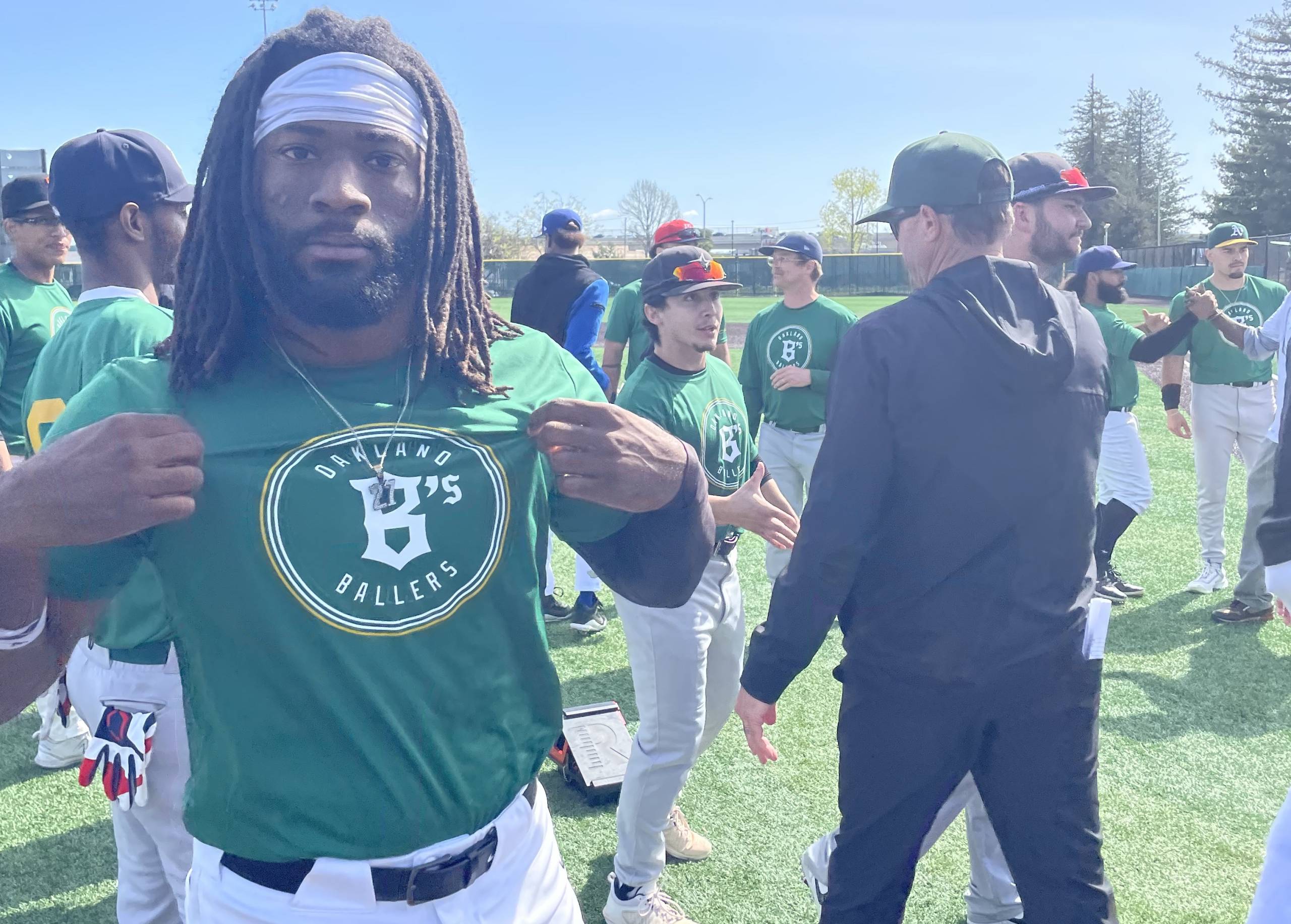 a baseball player shows off his Oakland Ballers jersey at a local tryout