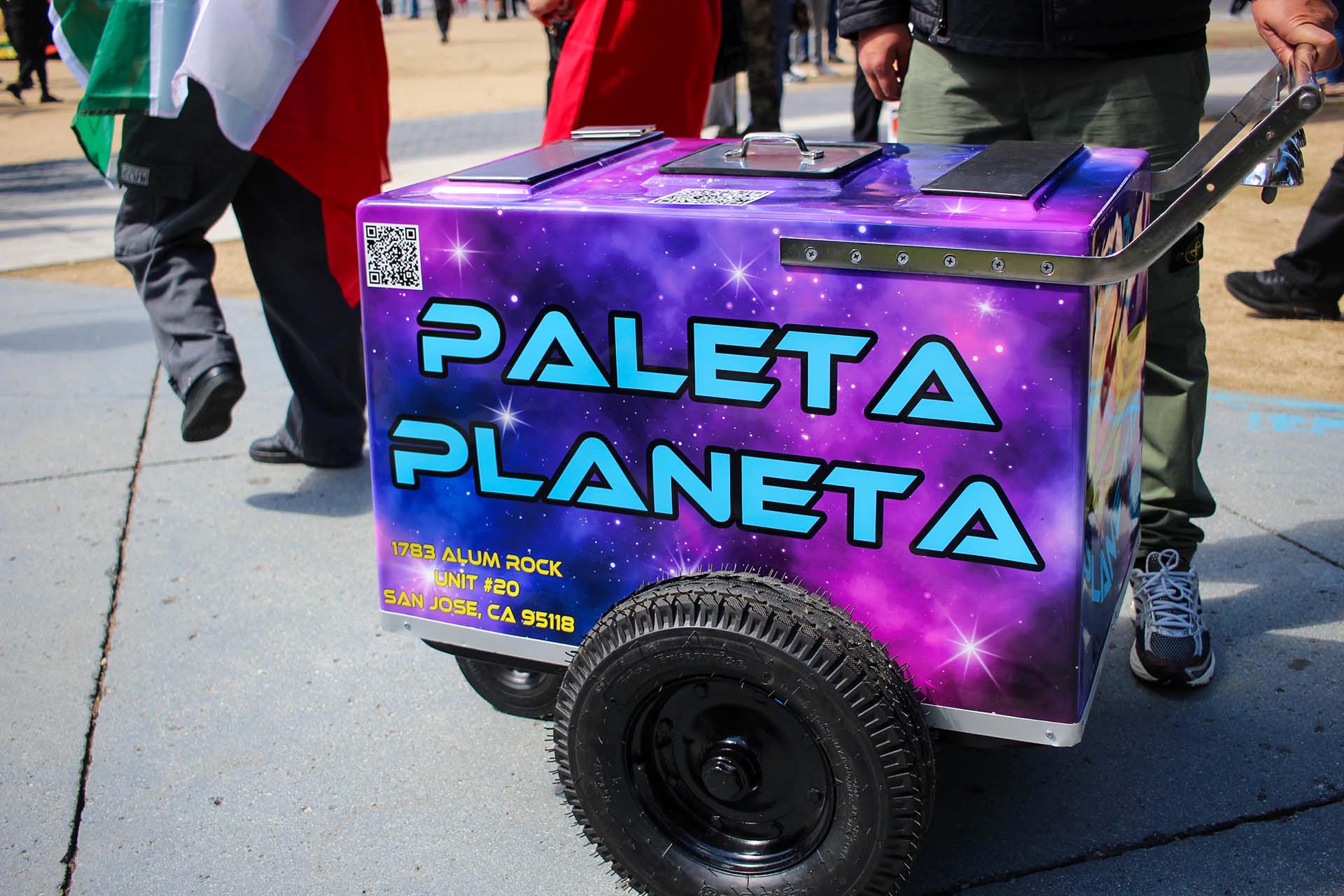 A purple, galaxy-themed paleta cart with the name of the business, "Paleta Planeta," in a space-age font. 