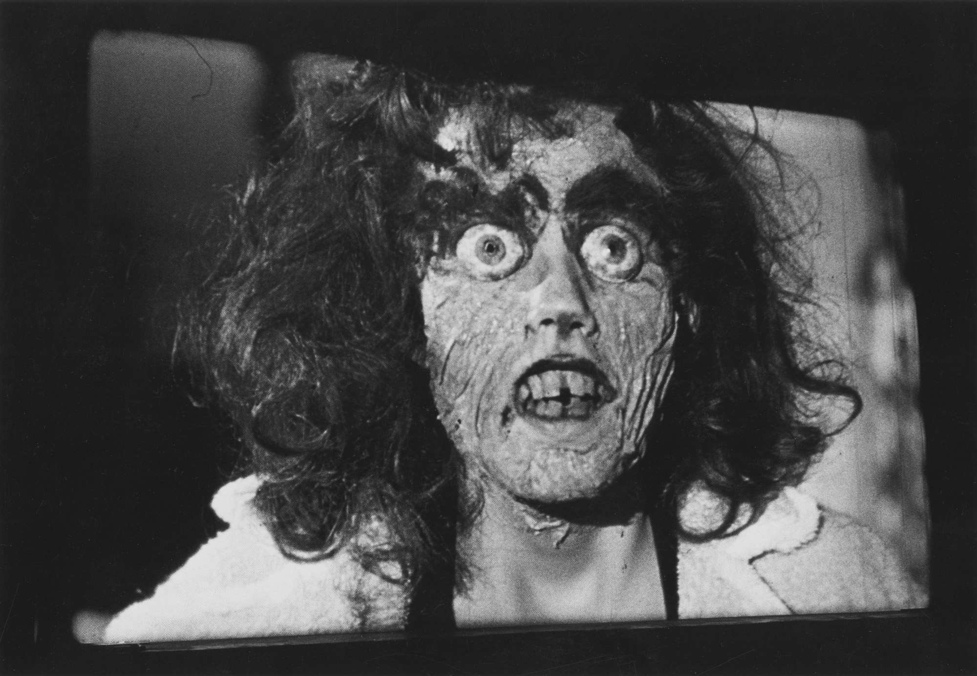 Black and white photograph of projected film of made-up monster face
