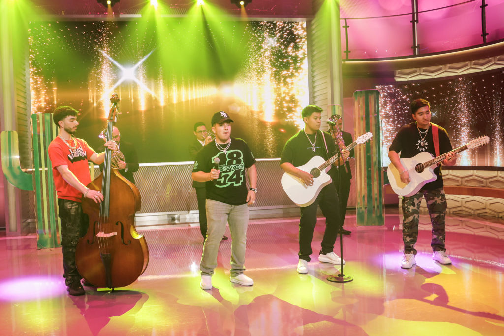A band performs on a brightly lit studio stage. 