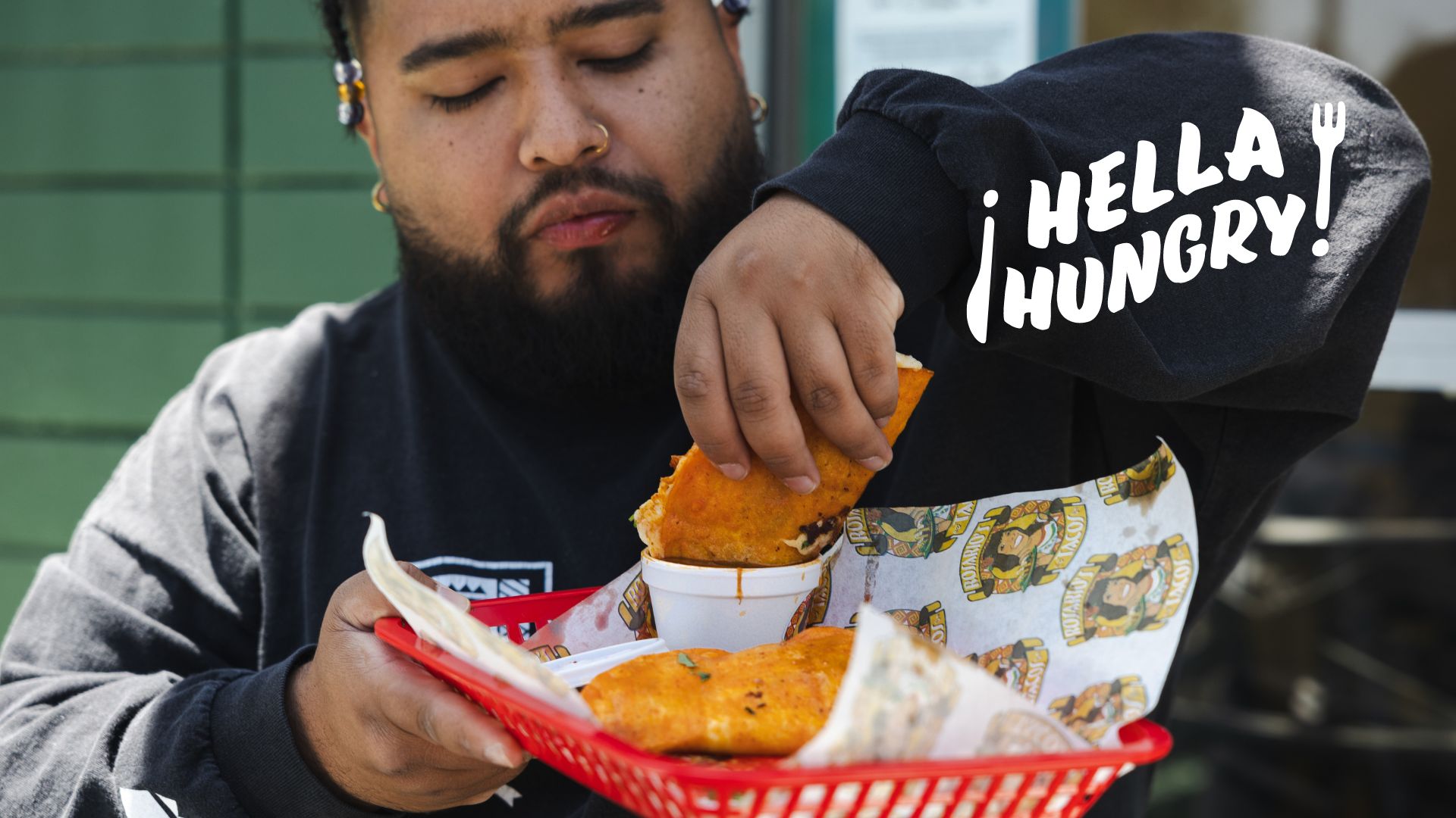 a Latino man prepares to eat a taco in front of a taqueria