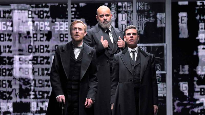 three men in antiquated suits look surprised, in front of a backdrop of stock tickers