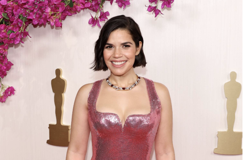 A Latina with short dark hair wearing a structured, sequined pink gown,