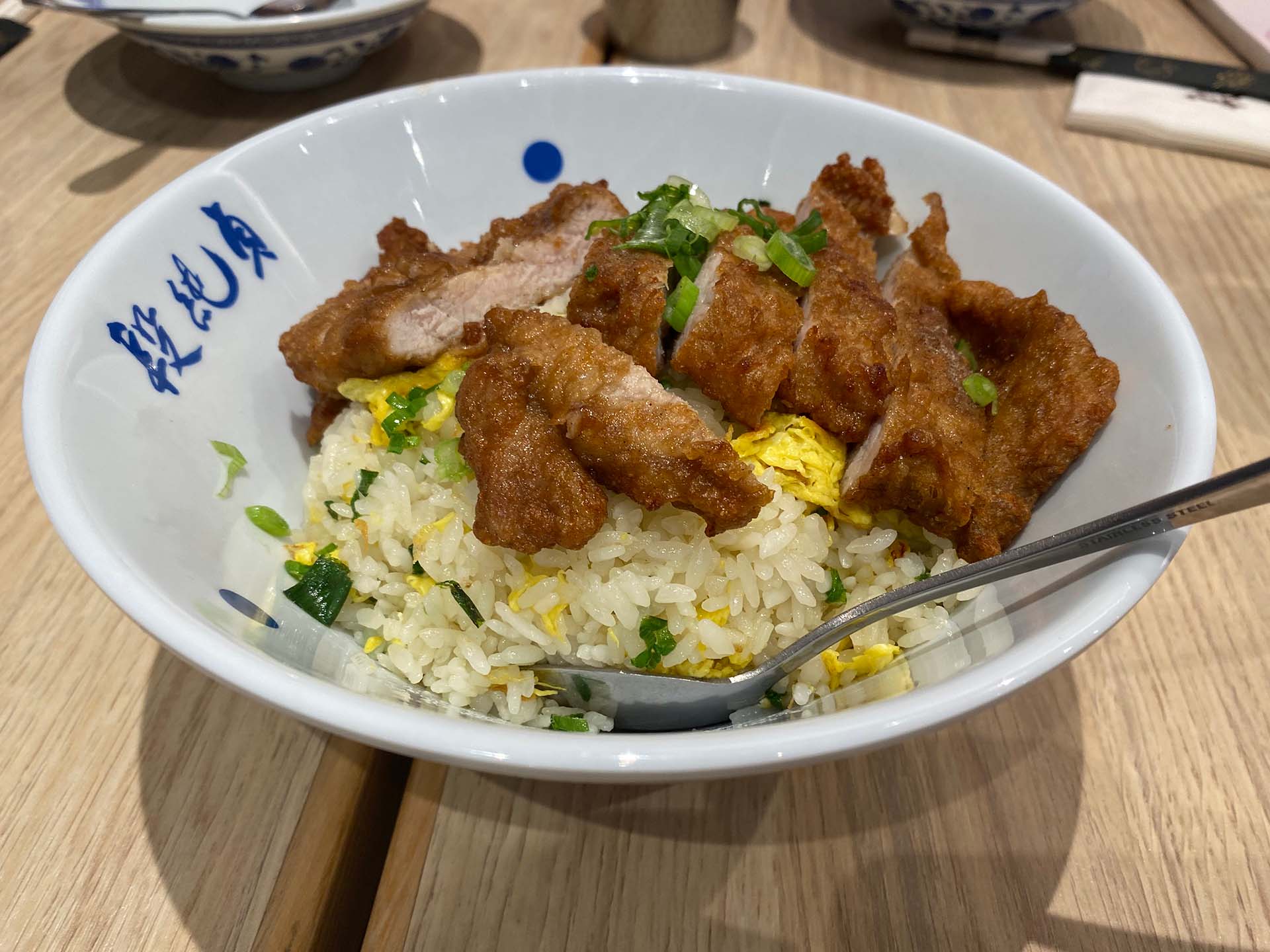A bowl of egg fried rice topped with fried chop.