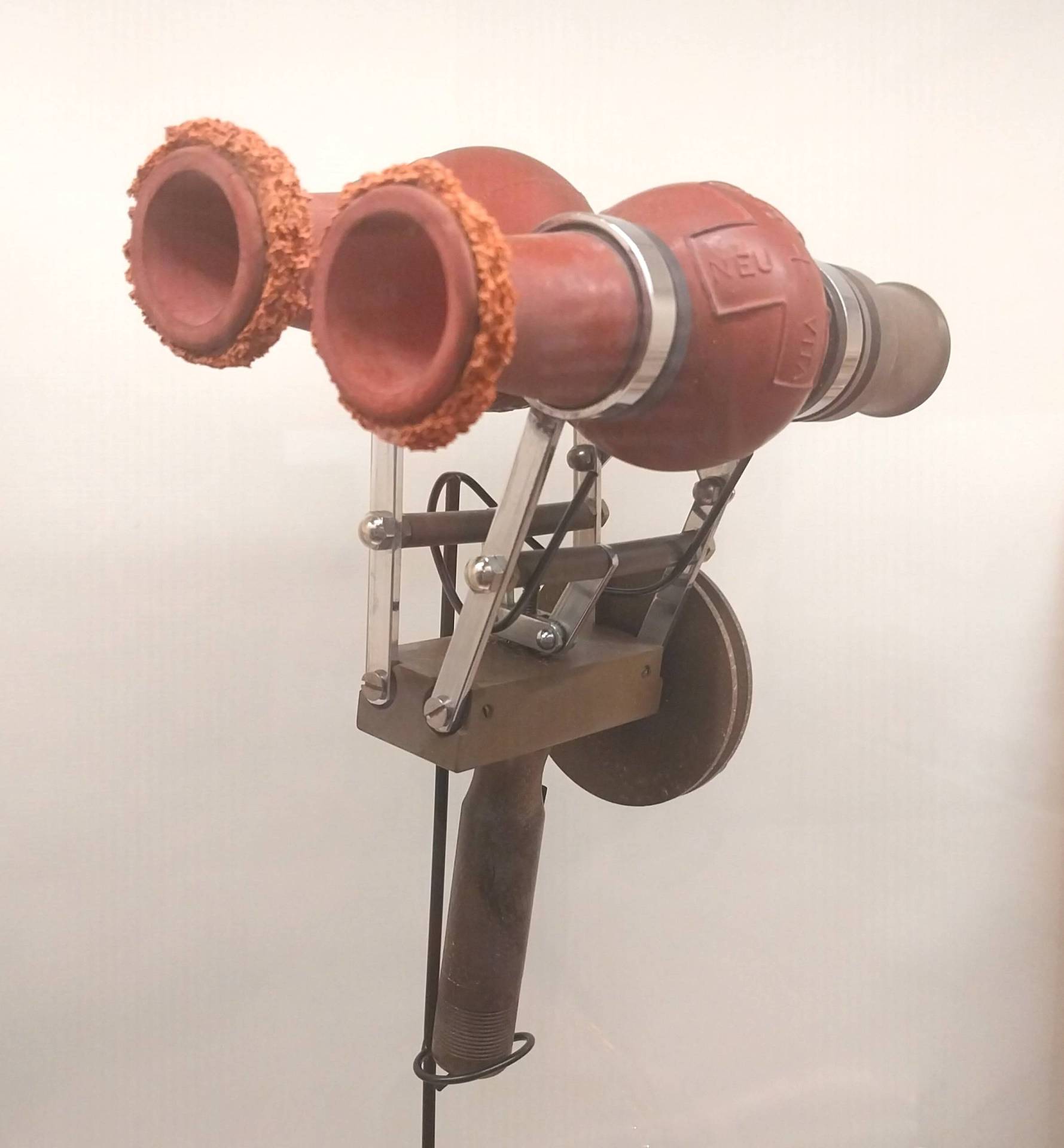 A rubber contraption resembling theater binoculars with a rotating device on the handle.