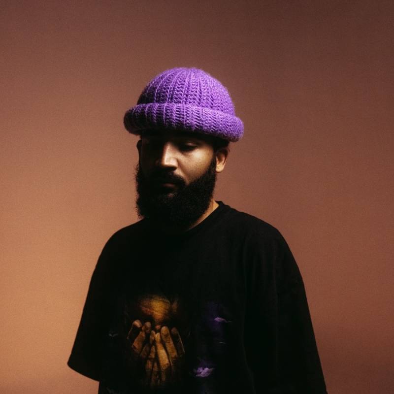 Nate Curry poses for a studio portrait wearing a purple knit beanie.