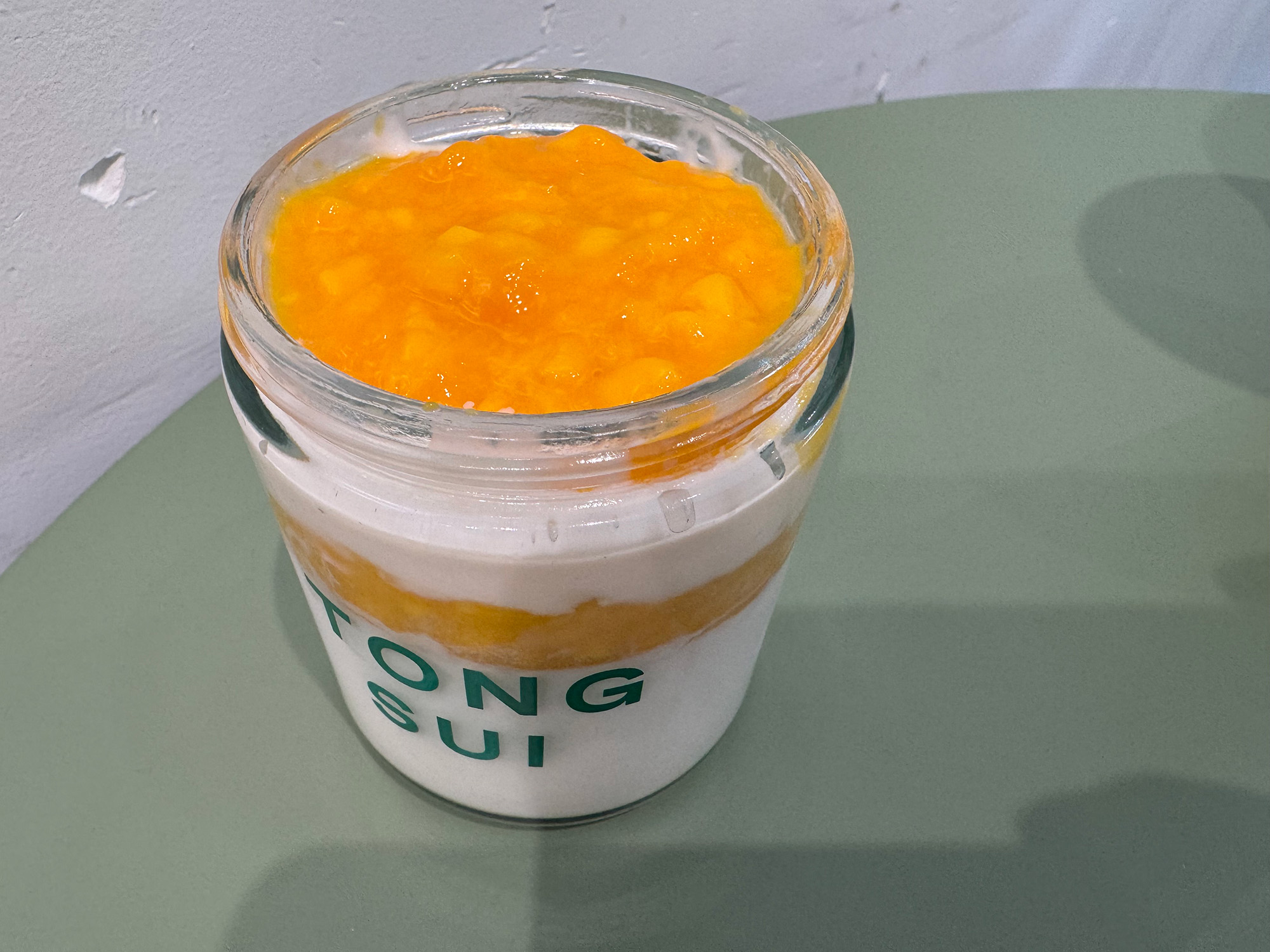 Coconut pudding topped with diced mango, served in a jar. The insignia on the jar reads, "Tong Sui."