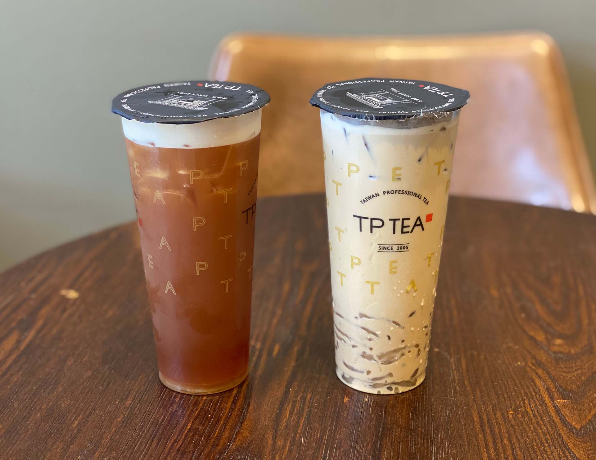 Two boba drinks on a wooden table.