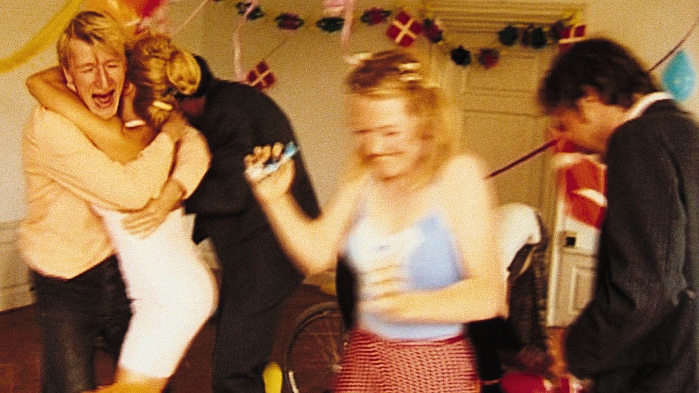 Group of people laugh, hug and dance, some blurred in motion