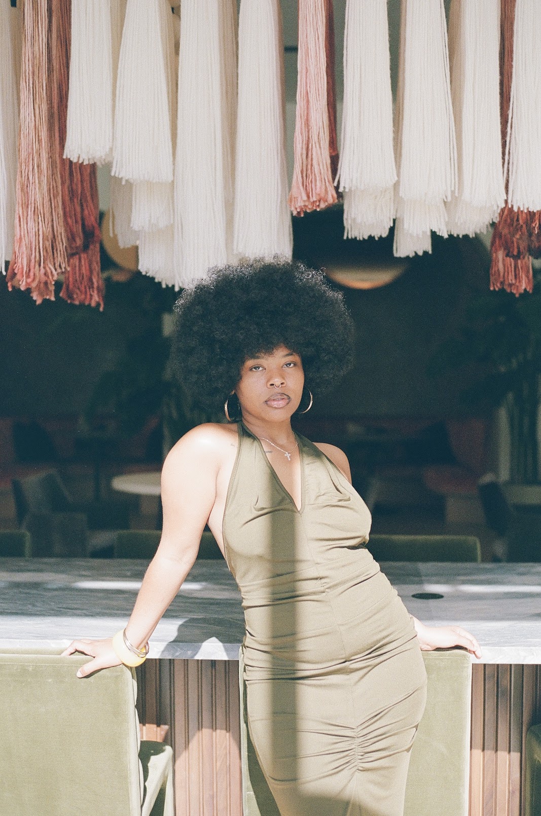 East Oakland R&B singer, Shanté, poses for a photo while wearing an olive dress.