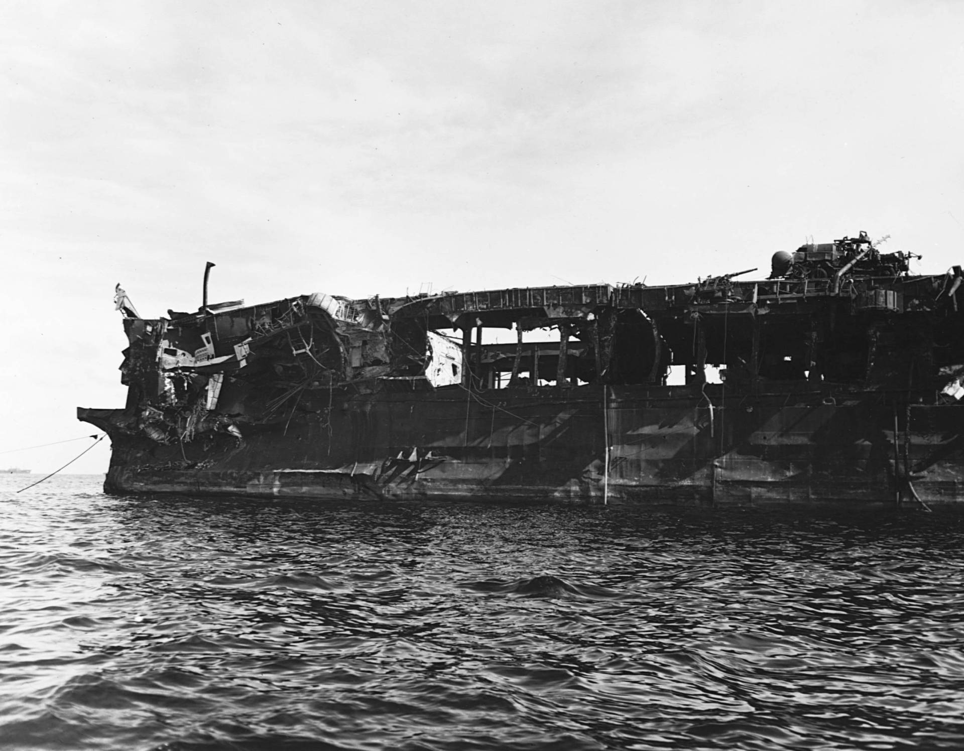 A war ship in unrecognizable, blackened ruins.