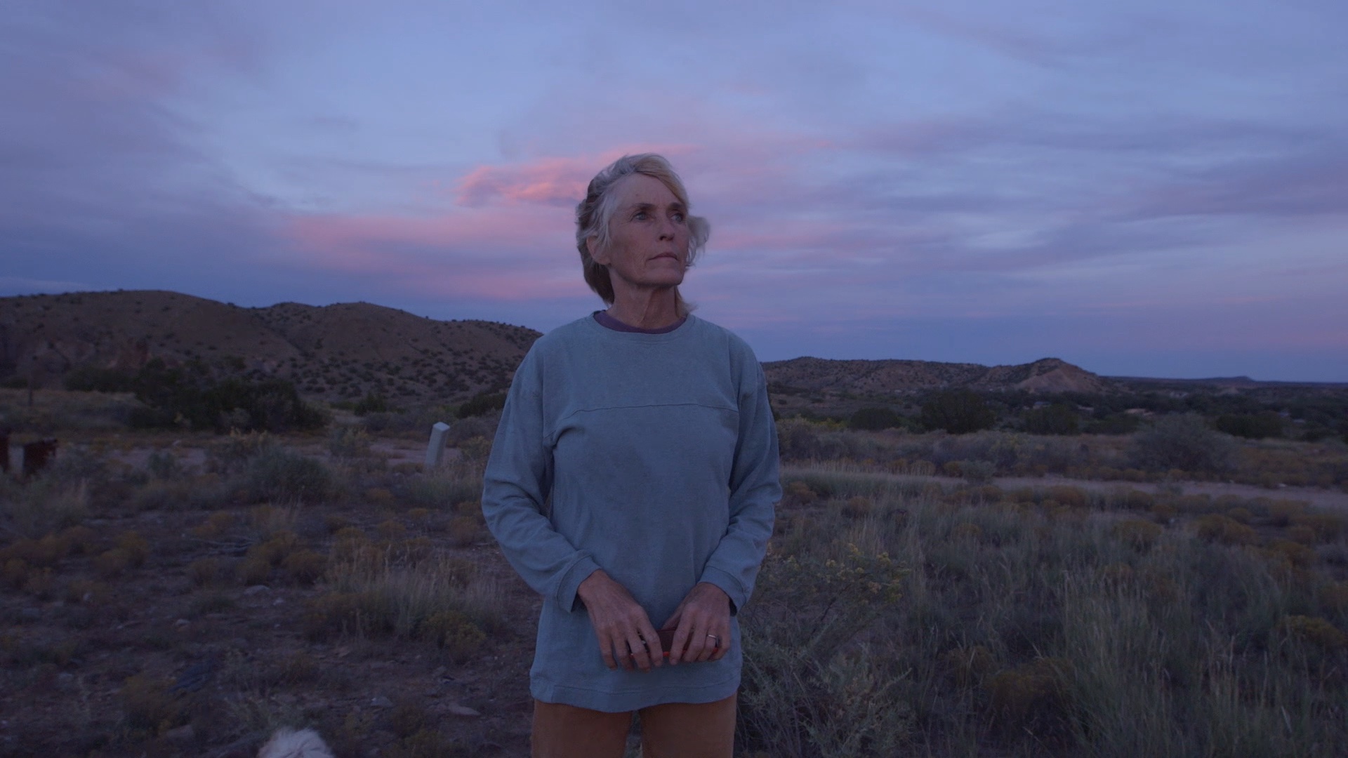Older woman in desert with dramatic sky behind
