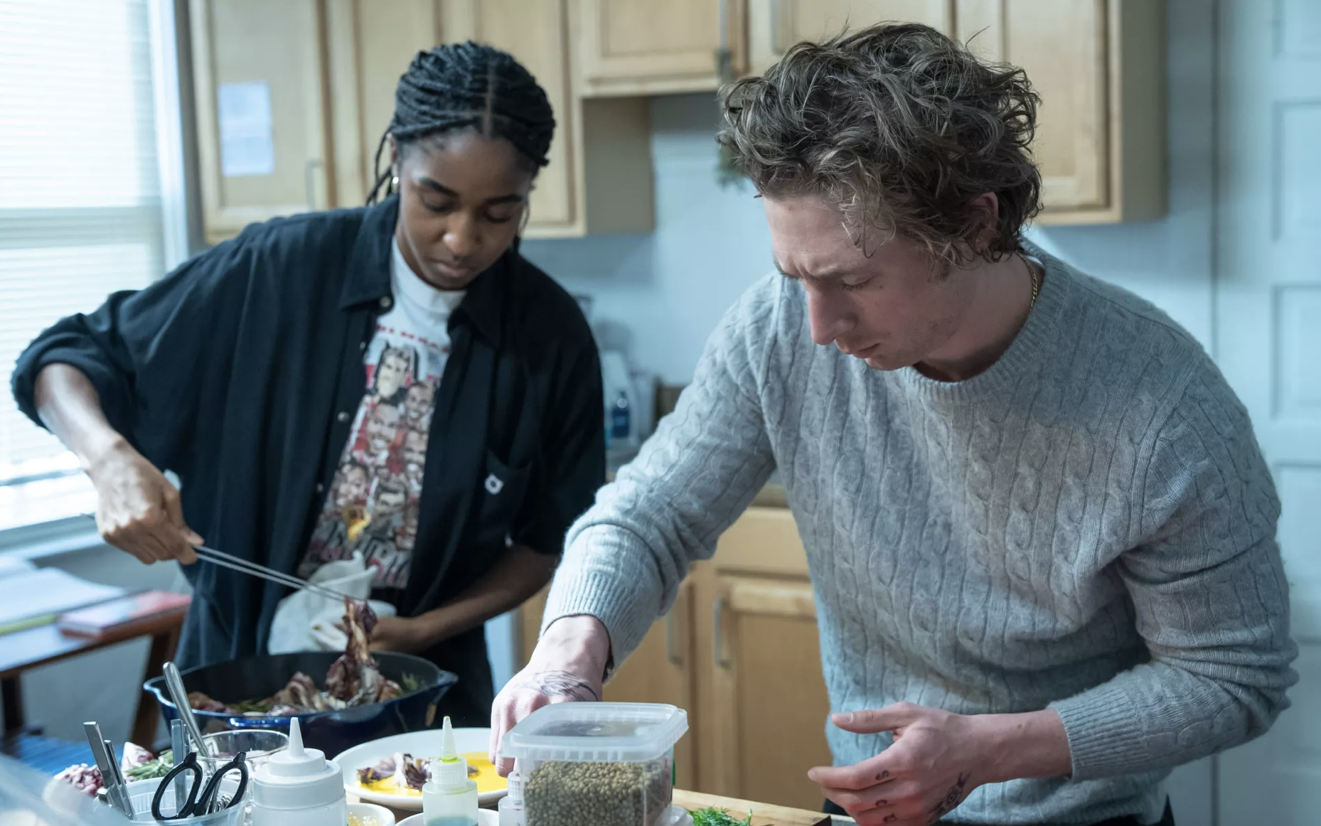 A white man and Black woman work side-by-side in a home kitchen.