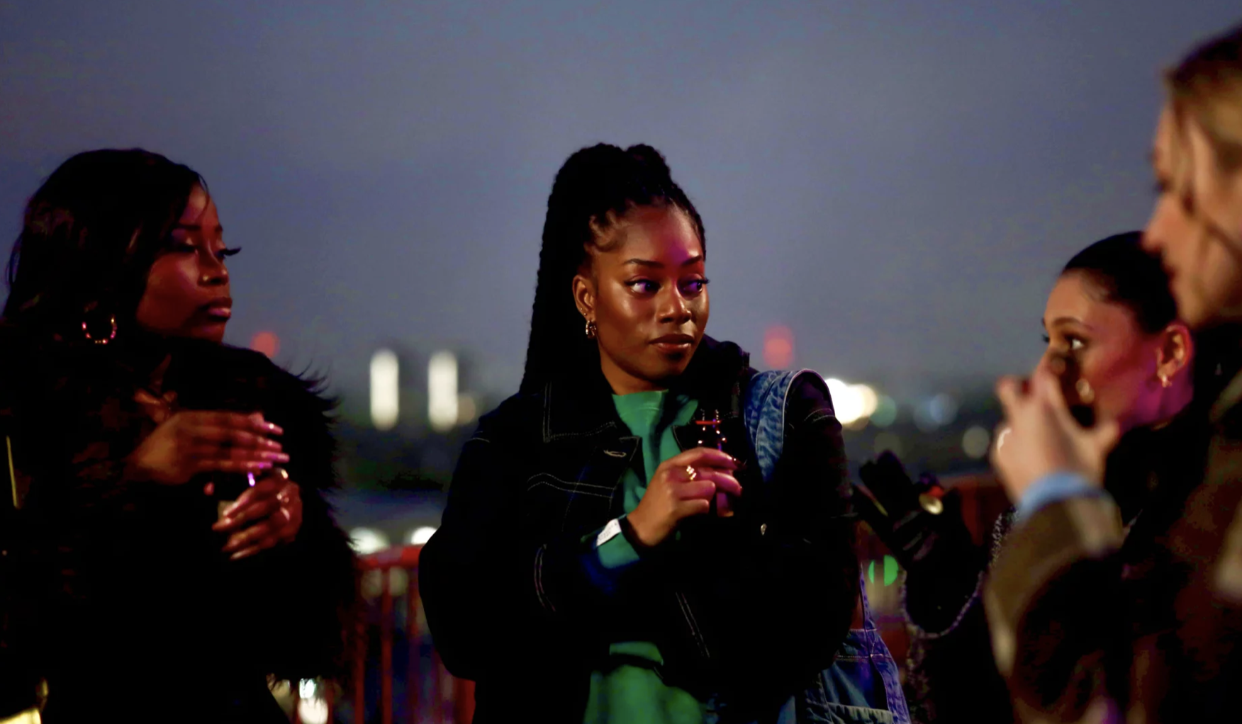 Two Black women stand outside at dusk, next to two white women.