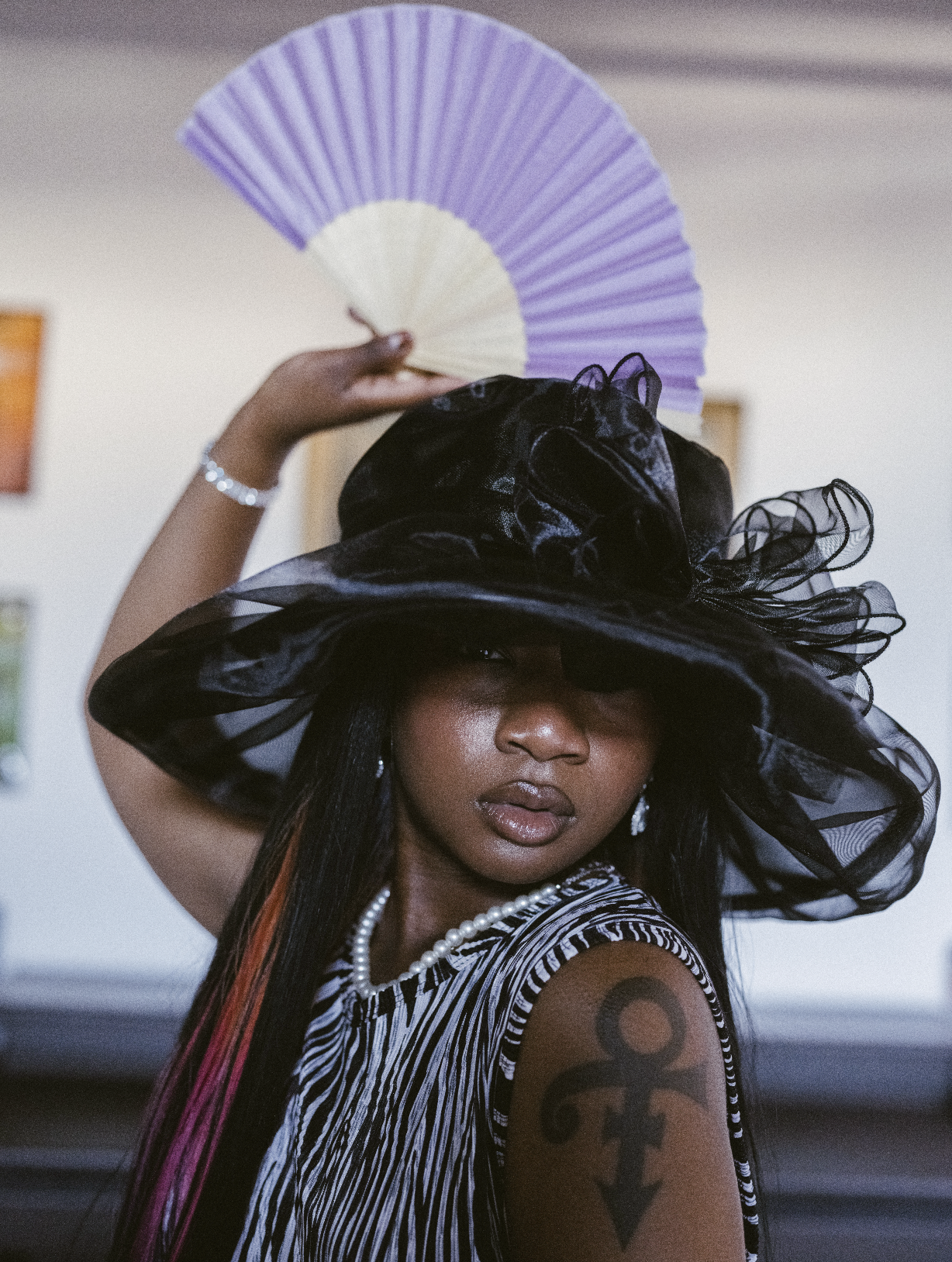 Singer and thespian, 3LISE, with a fierce black church hat and purple fan.