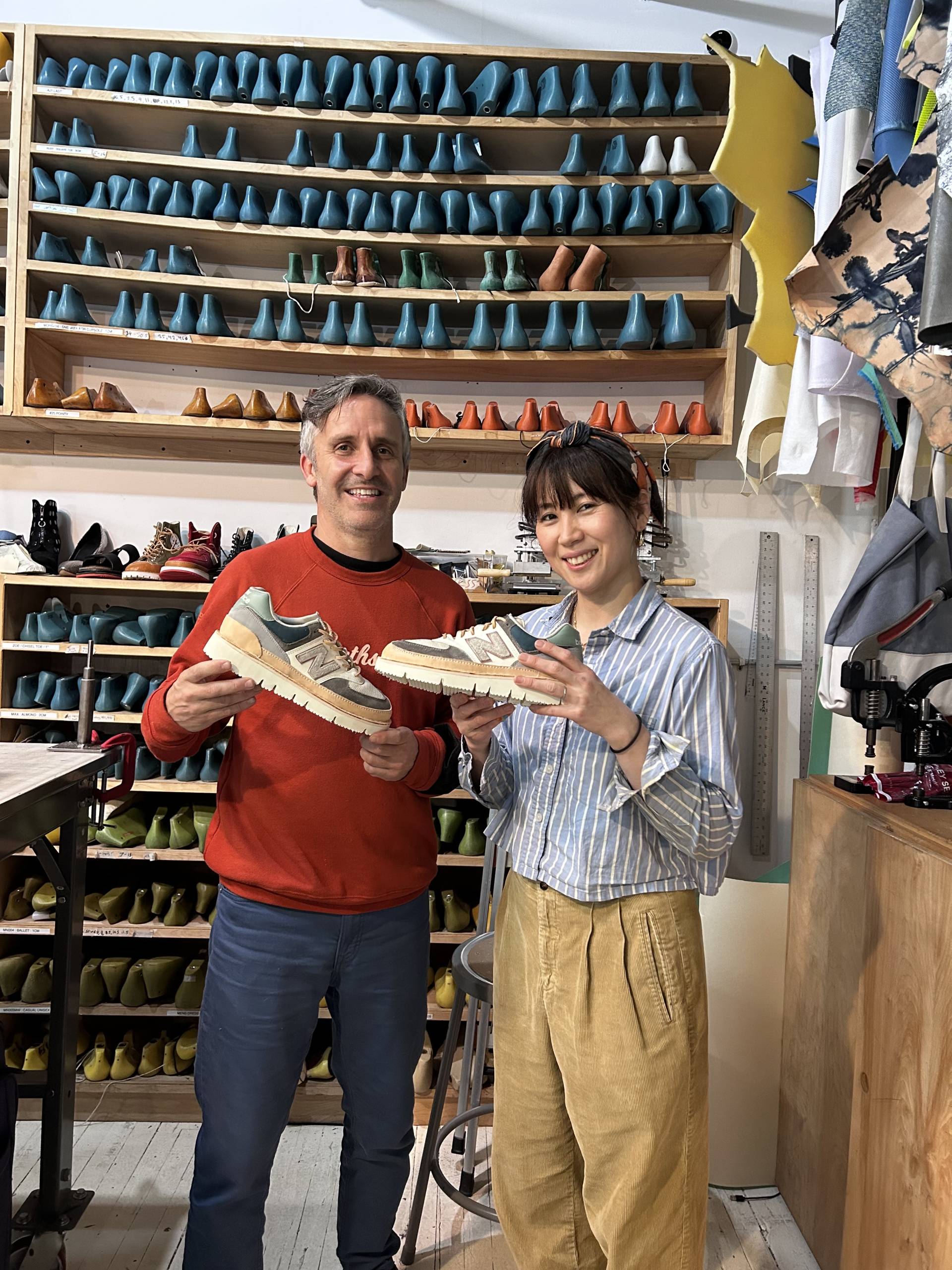 two shoe designers hold up their custom made pair of shoes