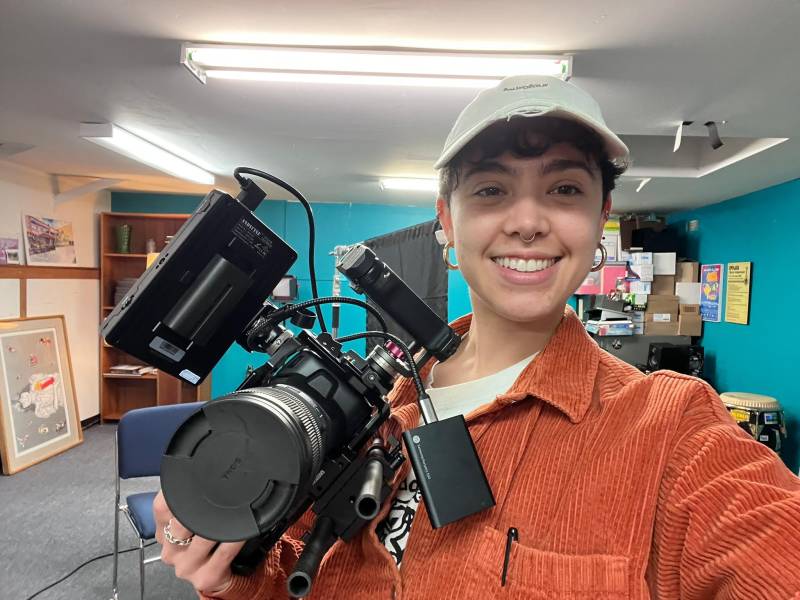 Filmmaker Clara Pérez, shown wearing their director's cap and holding a video camera.