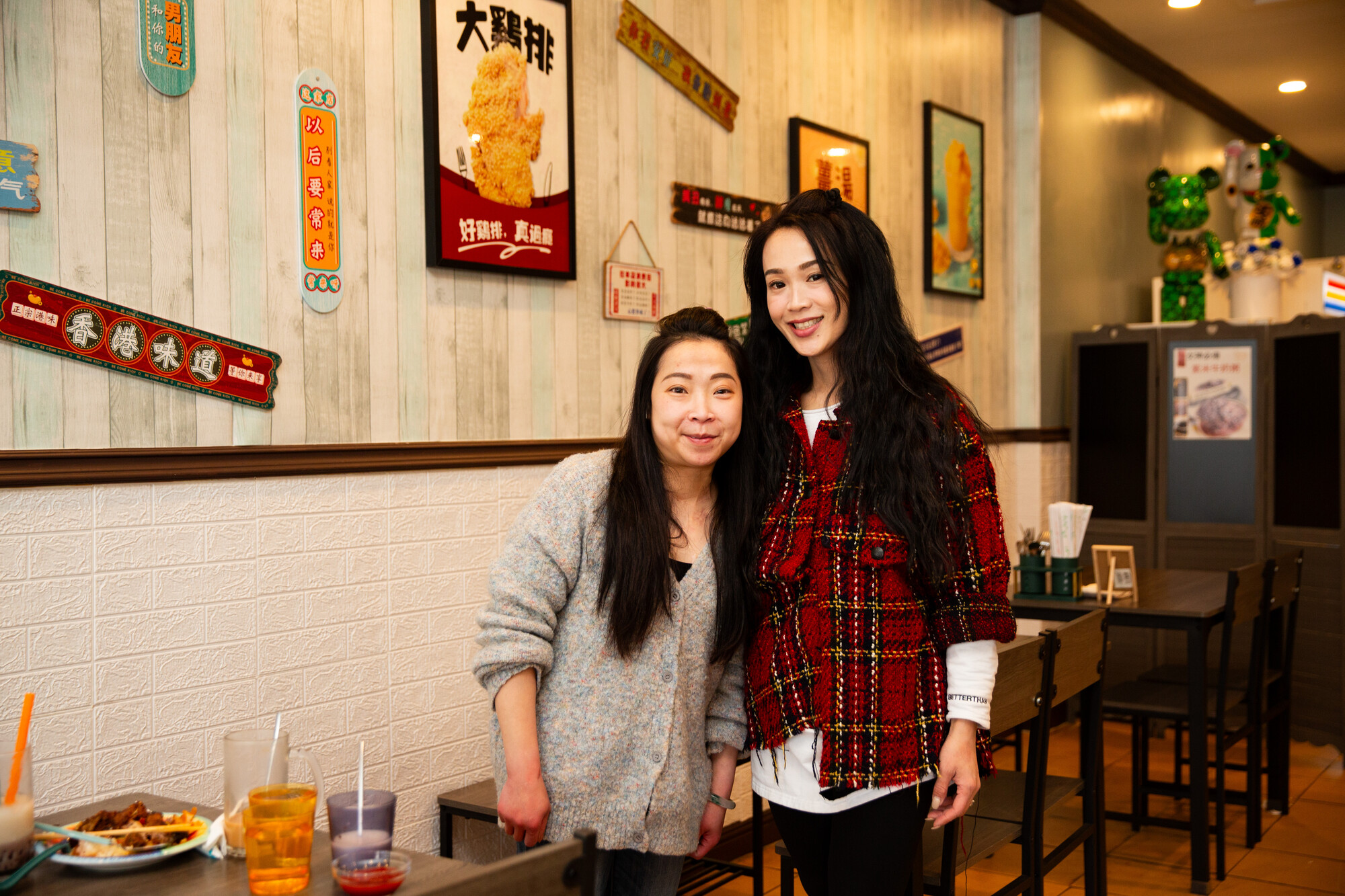 Two Asian women with long hair pose for a portrait inside a restaurant.