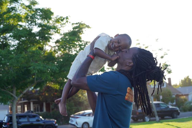 Man with locs holding a smiling baby.