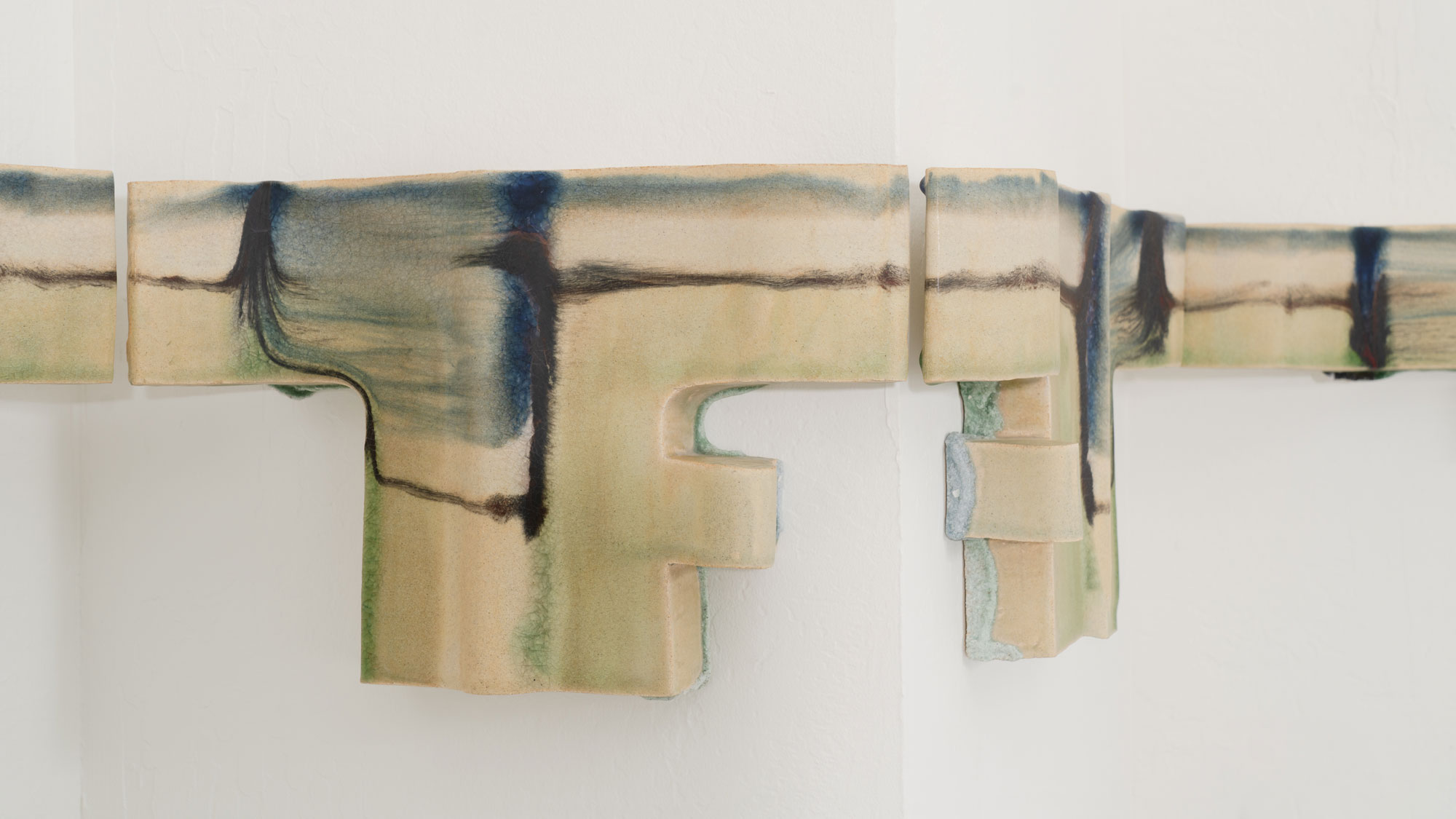 Detail of abstract glazed ceramic that covers a protruding corner in a white gallery space