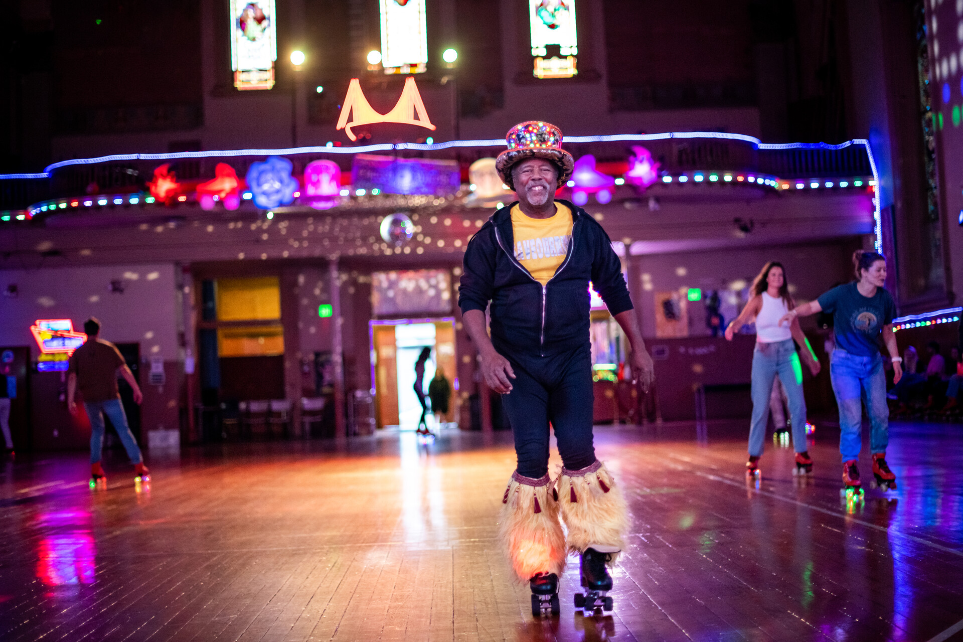 A roller skater smiles, skating in fur leg warmers and a top hat.