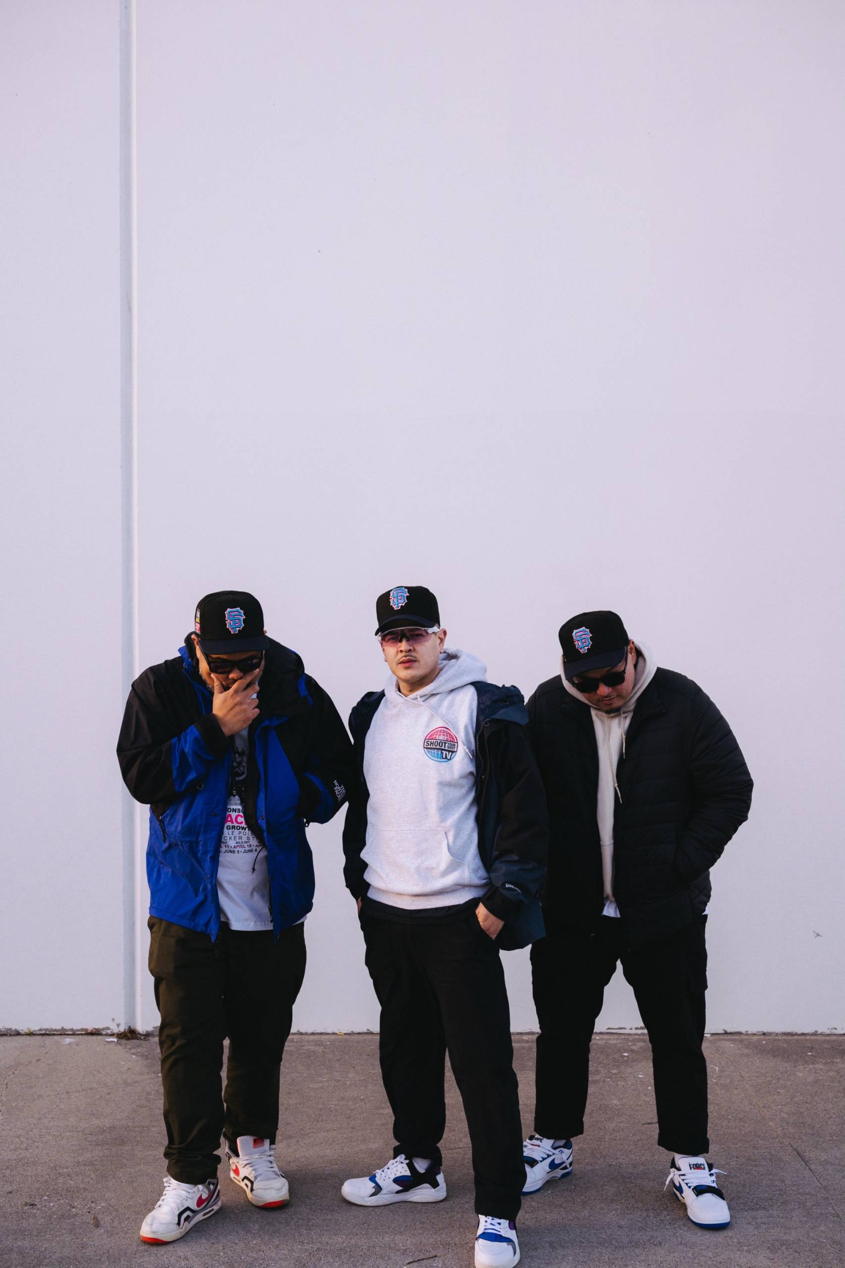 a group of three rappers stand outside in San Francisco-themed apparel