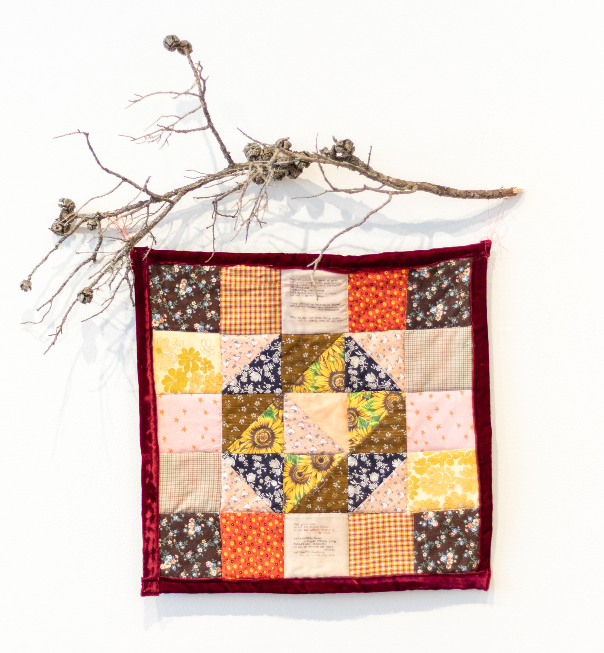 Quilted textile work with dried branch hanging above